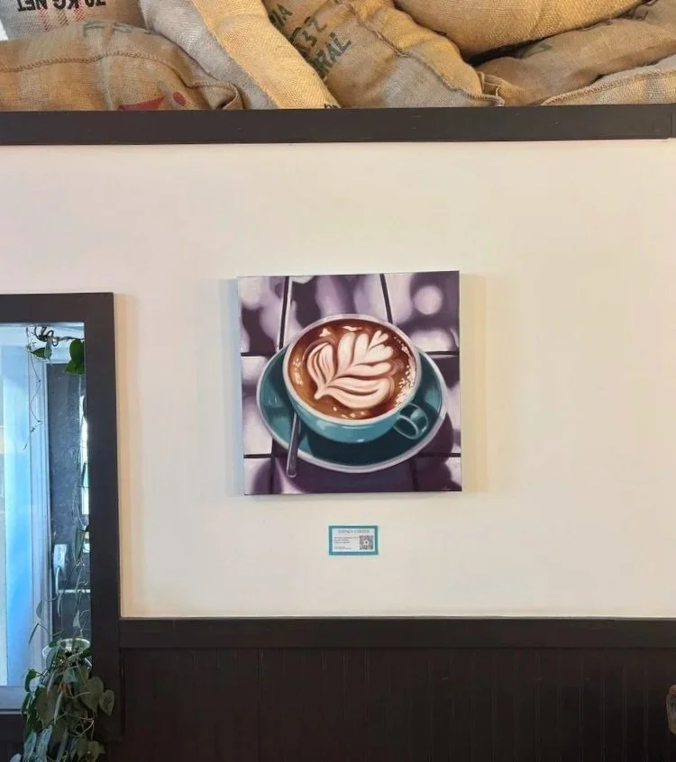 A painting of a coffee cup with latte art on top, placed on a small table.