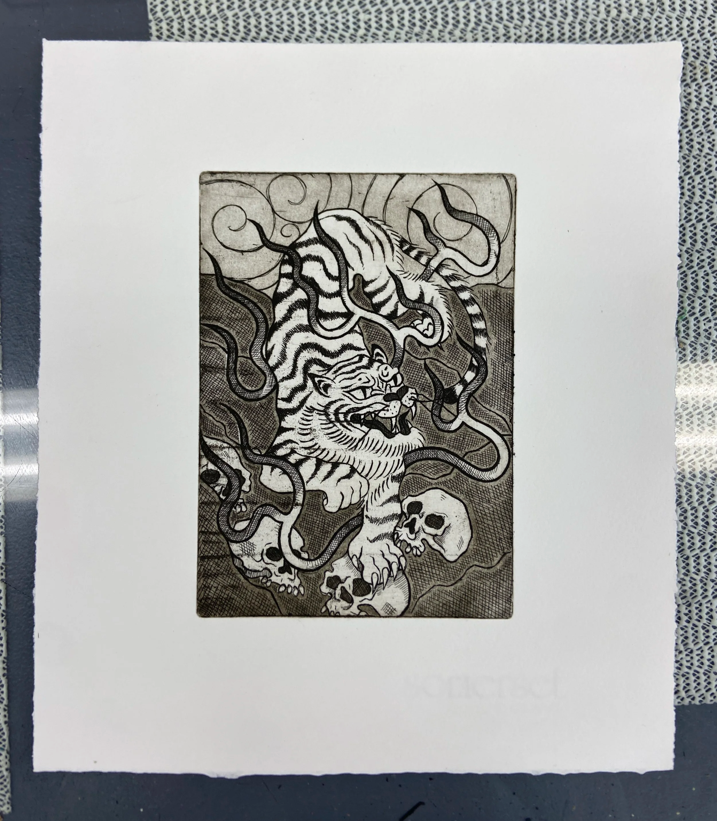 A black and white illustration of a fierce tiger with its mouth open revealing sharp teeth, and surrounded by swirling wind or smoke patterns.