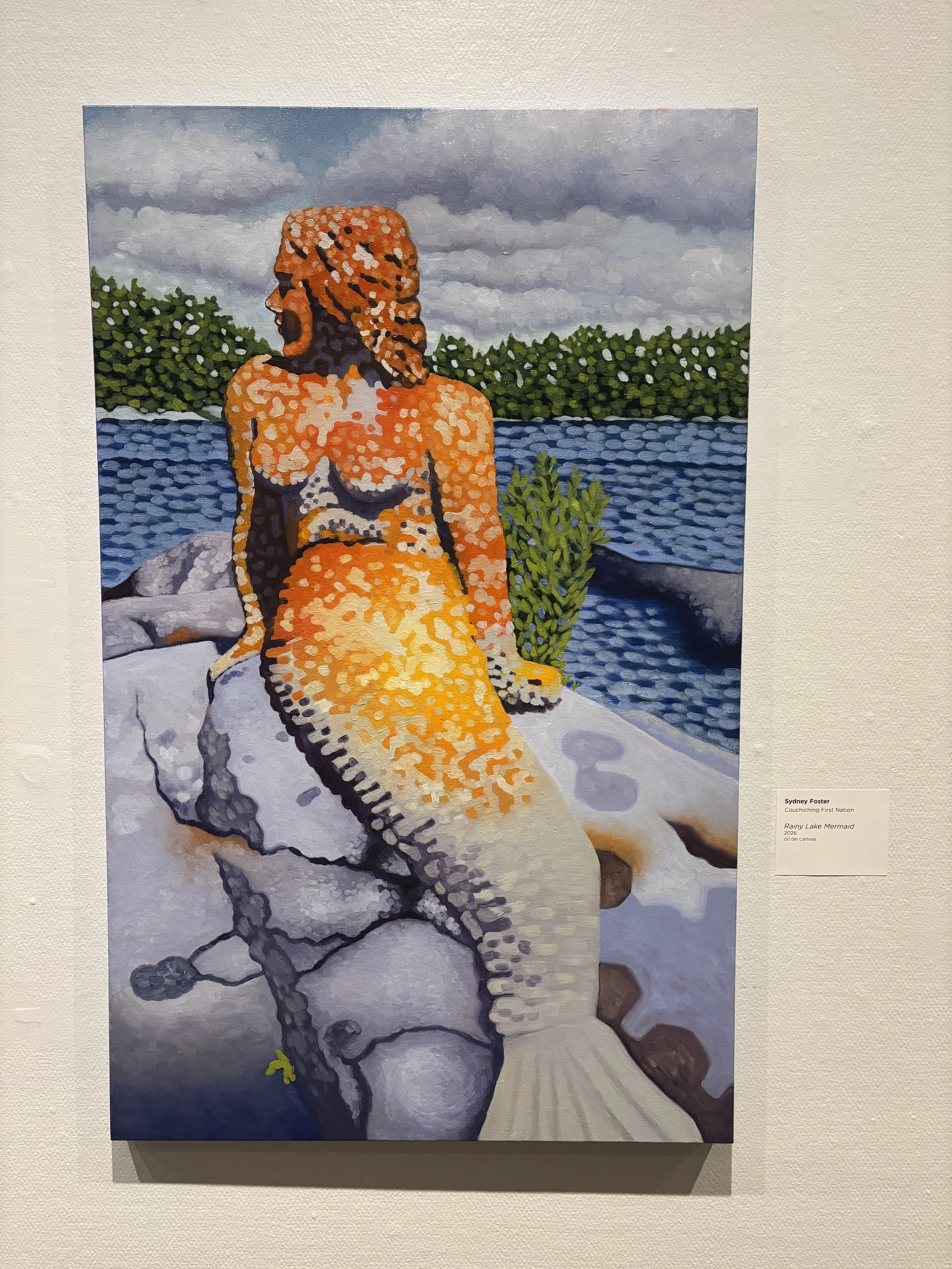 A painting of a mermaid sitting on a rock by a lake, also known as the 'Rainy Lake Mermaid,' with green bushes in the background, under a cloudy sky.
