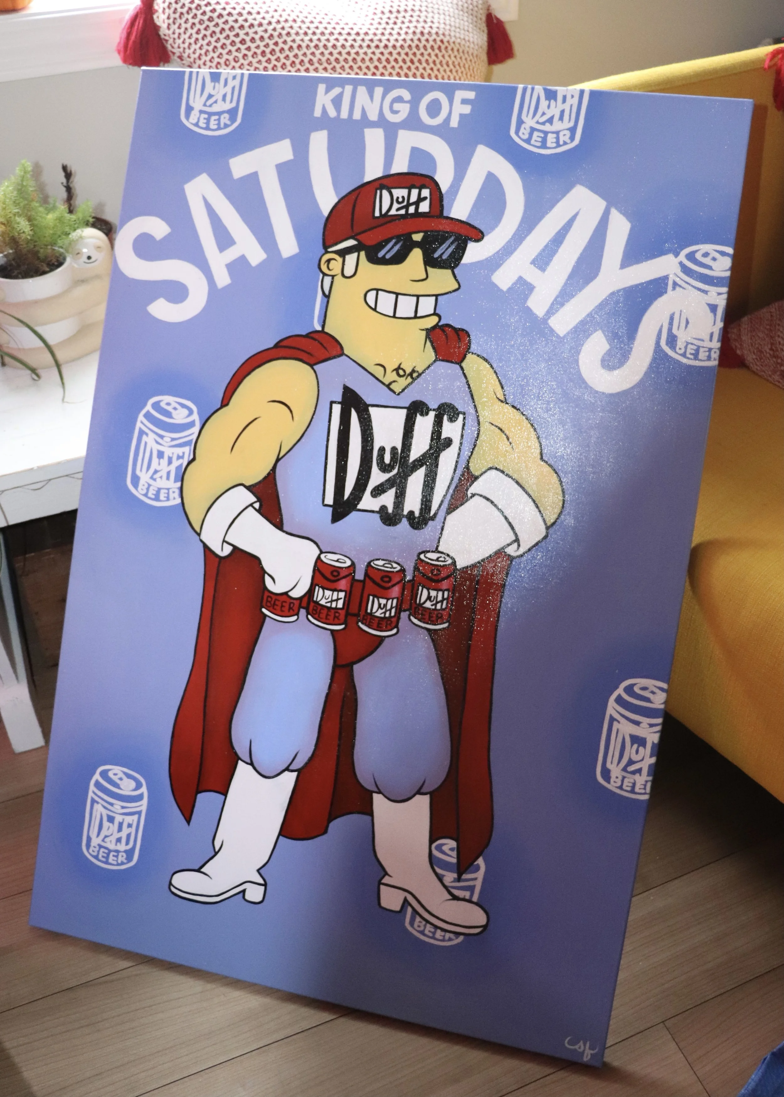 A colorful illustration of a superhero character with sunglasses, a red cap, and a red cape, holding cans of beer, with a background featuring the phrase 'King of Saturday' and beer cans.