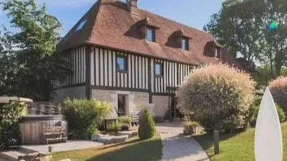 Maison à colombages avec un jardin bien entretenu et un arbre en floraison.
