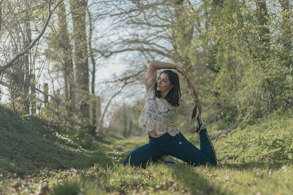 Une femme effectuant une pose de yoga dans un bois verdoyant au printemps.