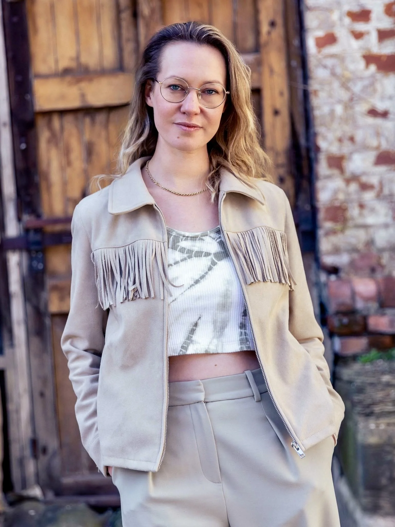 Alice standing in an industrial setting, looking to camera and smiling slightly. Photo by Mark Ratcliffe.