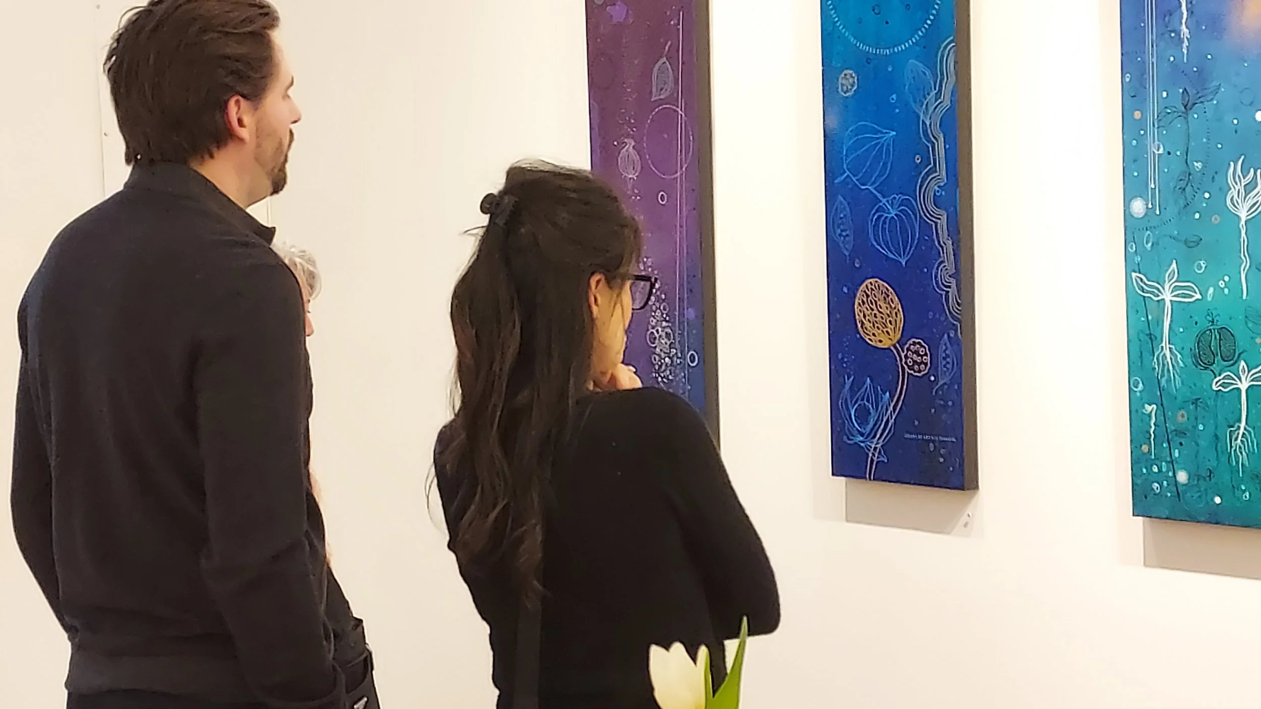 visitors looking at paintings by artist Heather Stivison in her solo exhibition "Seeds of Change"e