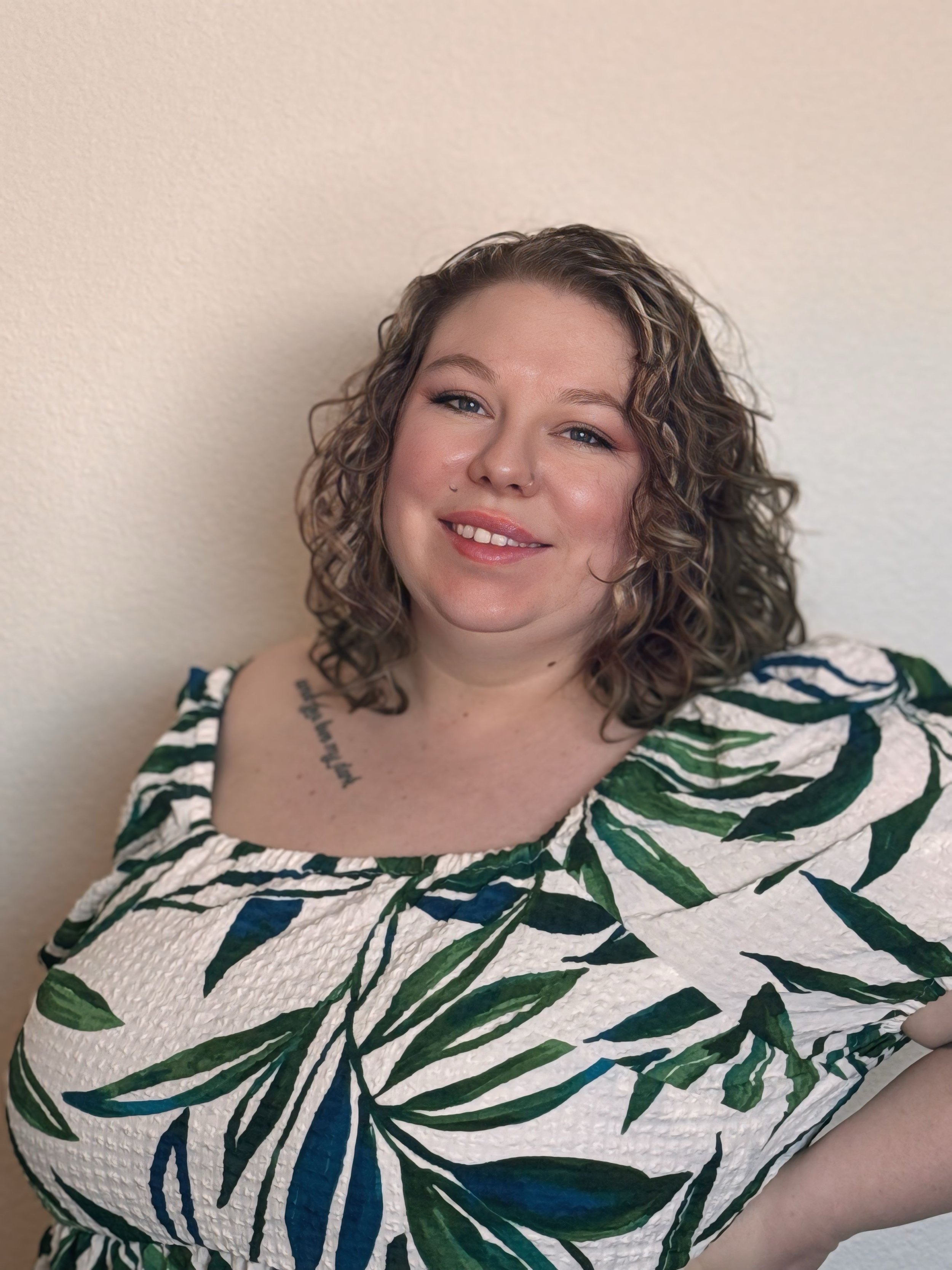 Sarah Gajewski with curly hair smiling, wearing a shirt with a green and white leaf pattern.