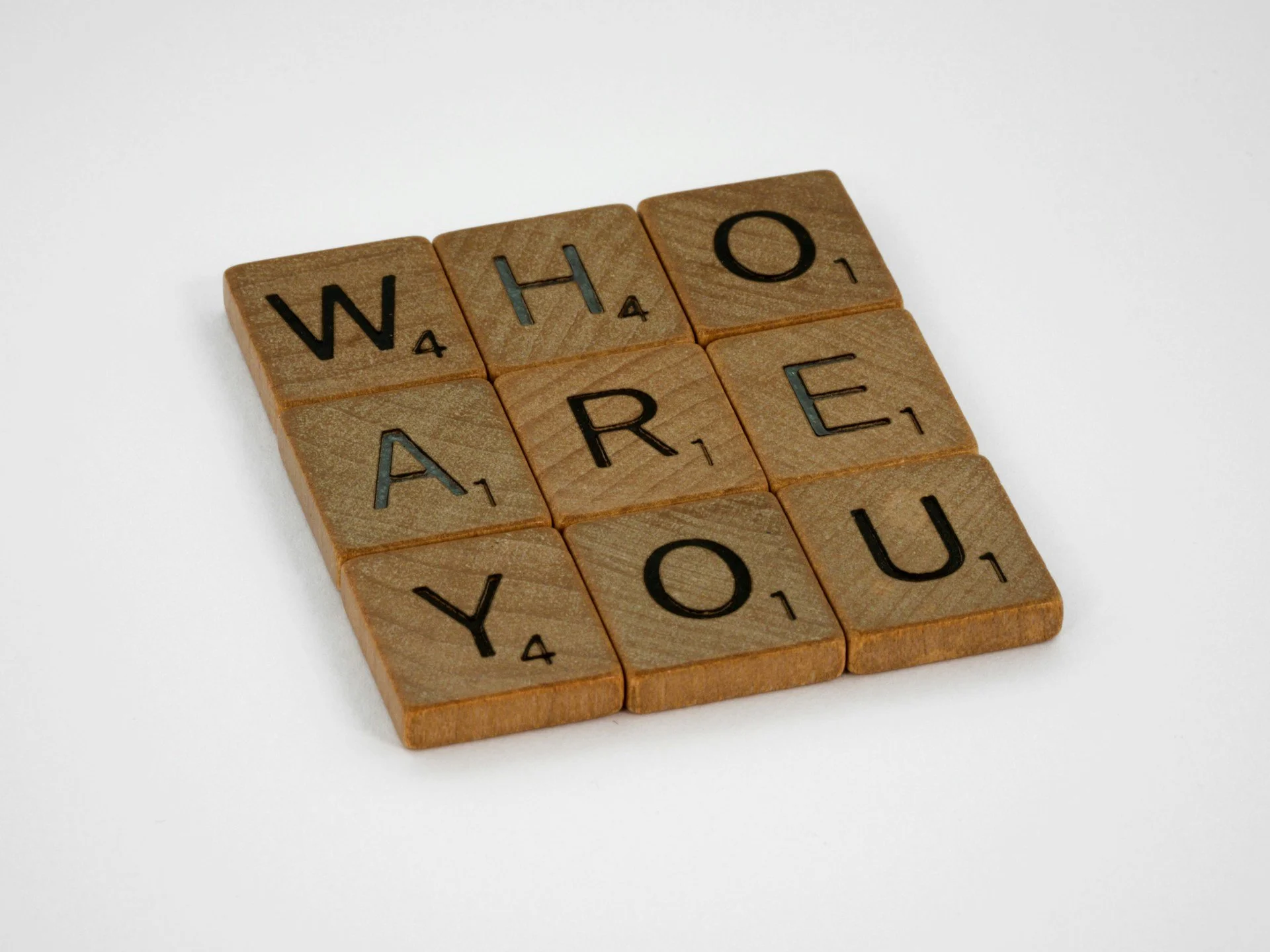 Holzwürfel mit Buchstaben und Zahlen, die das Wort "WHO ARE YOU" bilden, auf weißem Hintergrund.
