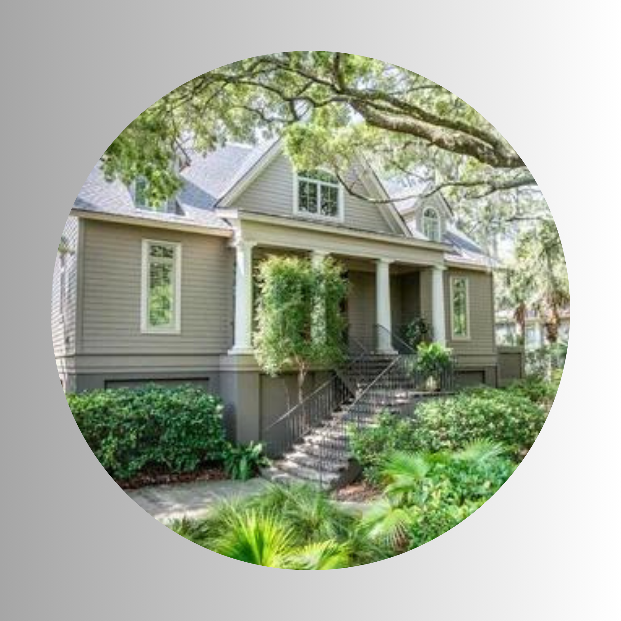 View of a house with a gray roof and siding surrounded by green trees and bushes.