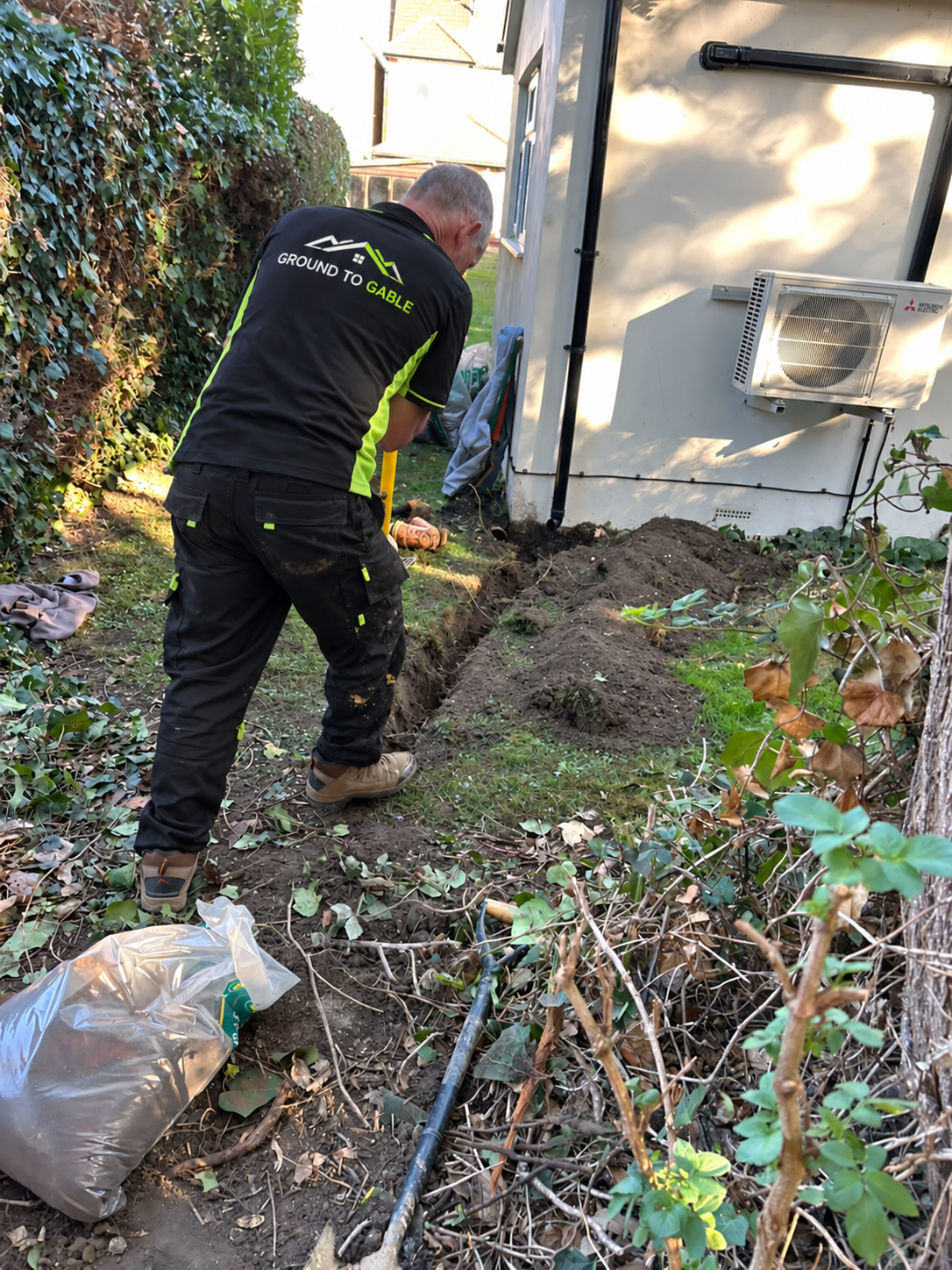 Hand excavation beside a house during a Ground to Gable soakaway installation