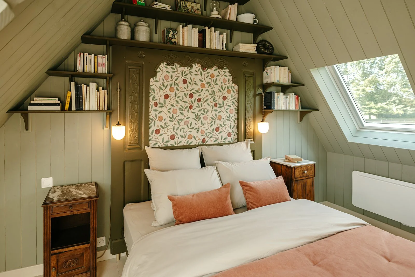 Chambre Dulse du Clos des Sentiles avec lit double, oreillers blancs et coussins roses, étagères remplies de livres, fenêtres de toit et ambiance cosy.
