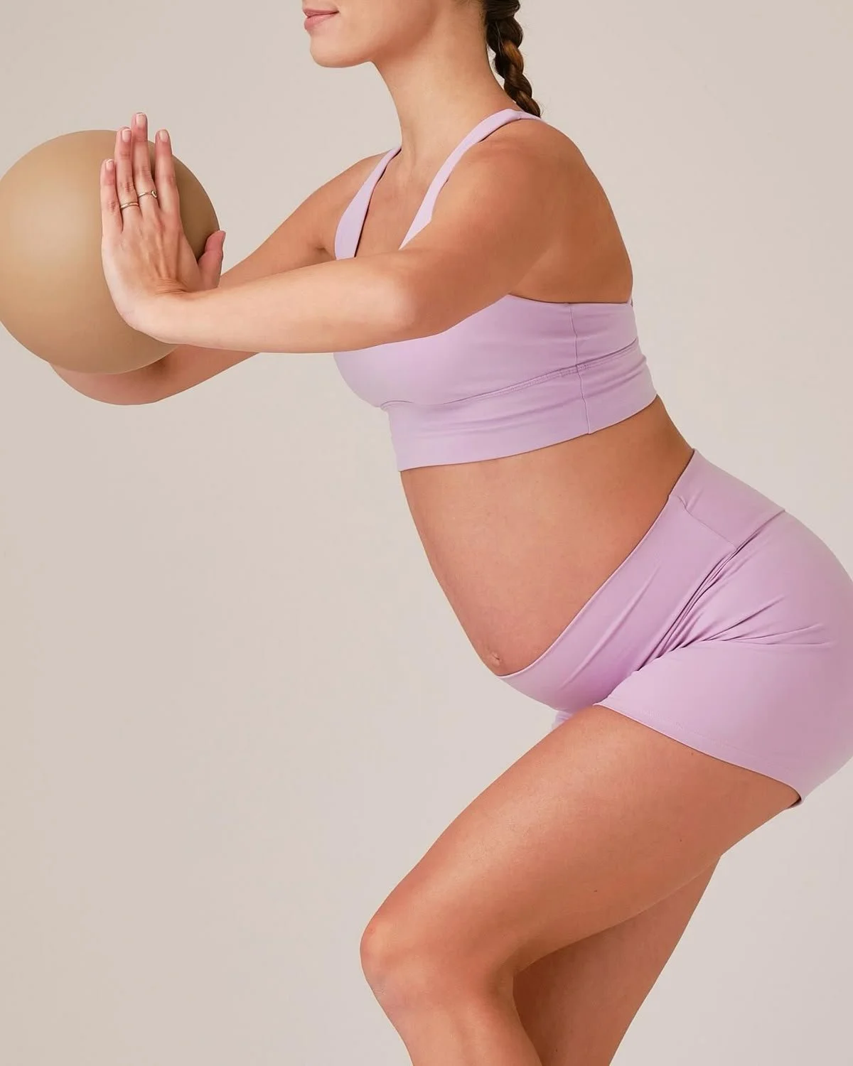 Femme enceinte en tenue de sport rose, faisant de l'exercice avec un ballon