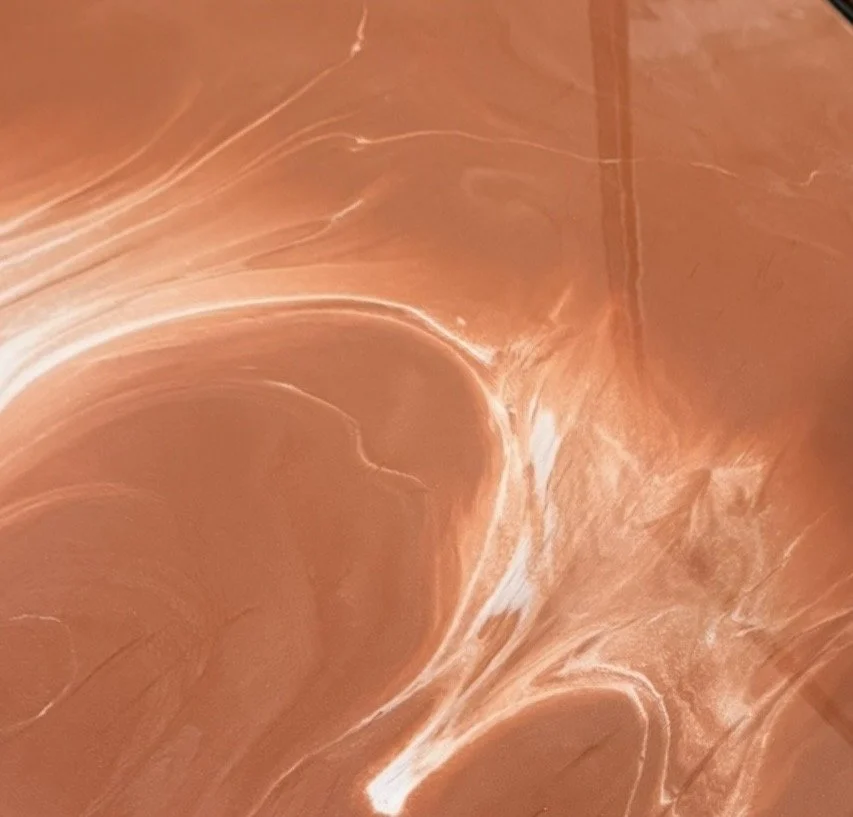 Close-up of a Metallic Epoxy System that resembles marble or polished stone surface with swirling copper and white patterns.