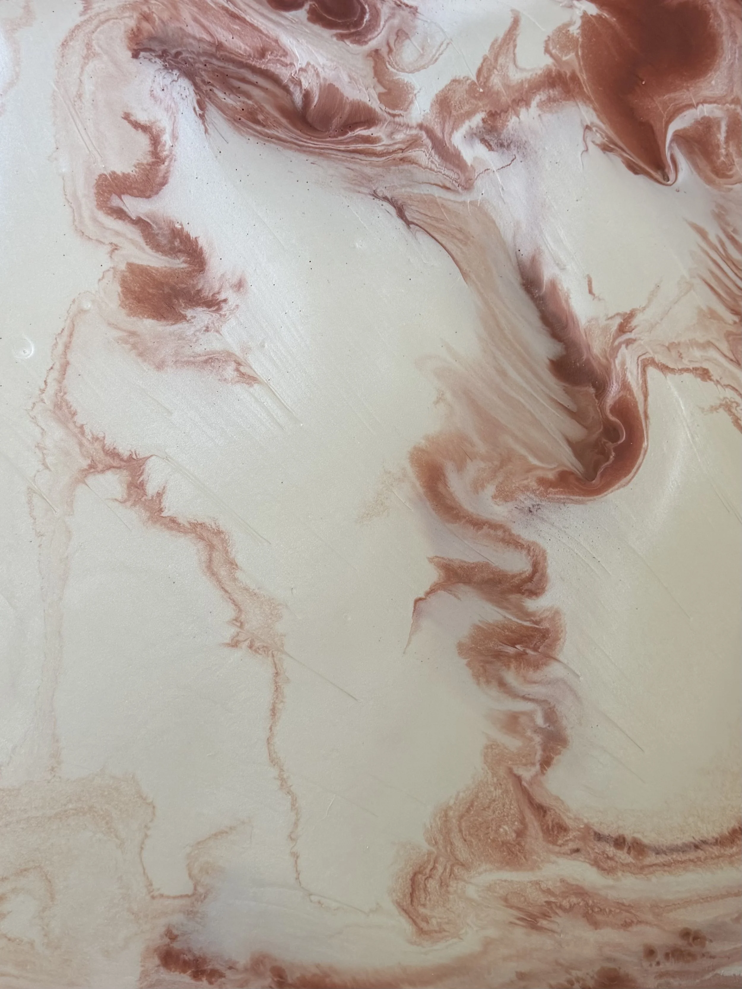 Metallic marbled artwork with swirls of white and reddish-brown hues.