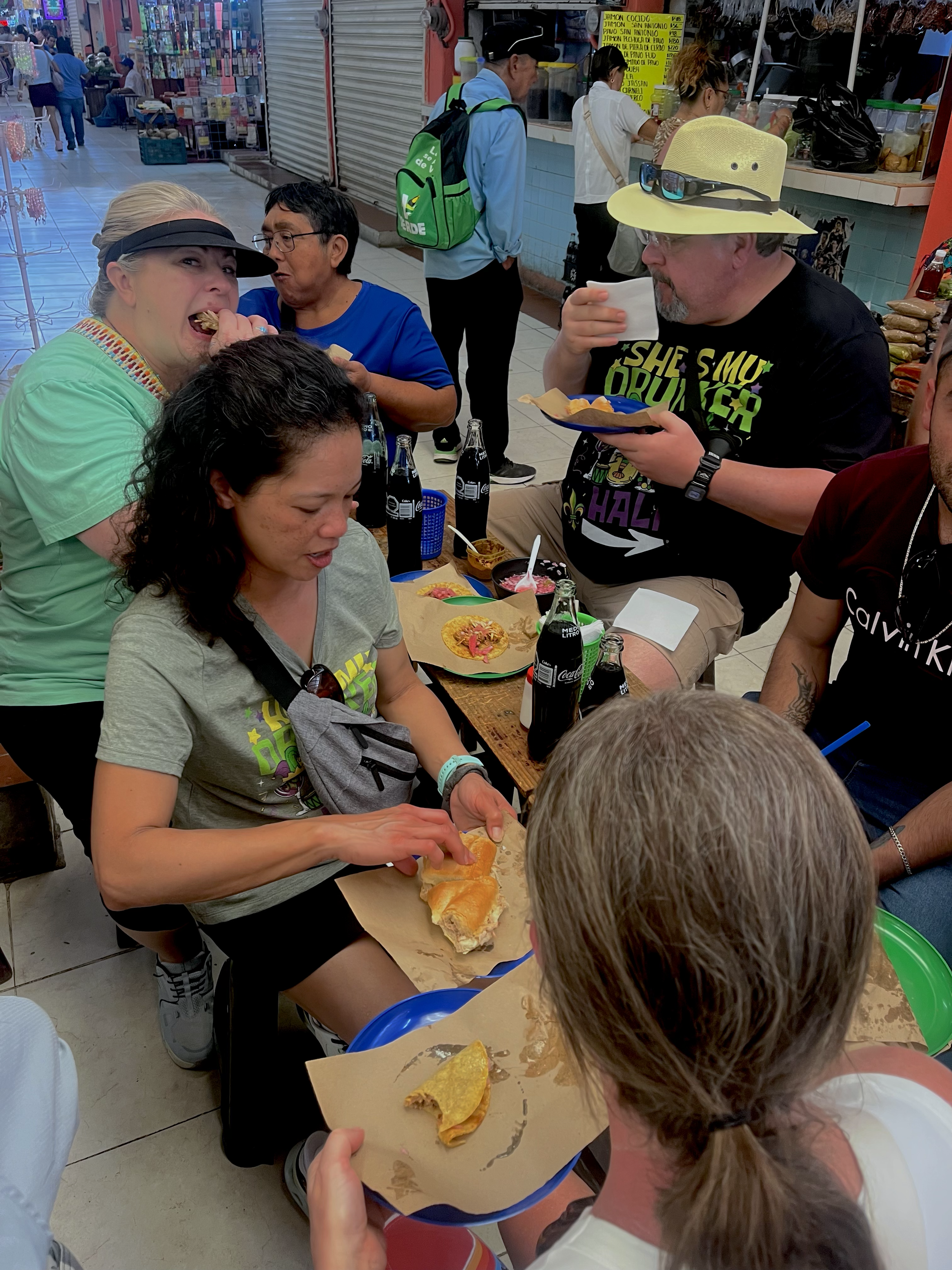 Travelers tasting tacos and traditional Yucatecan food at a local market in Mérida, Yucatán, Mexico.