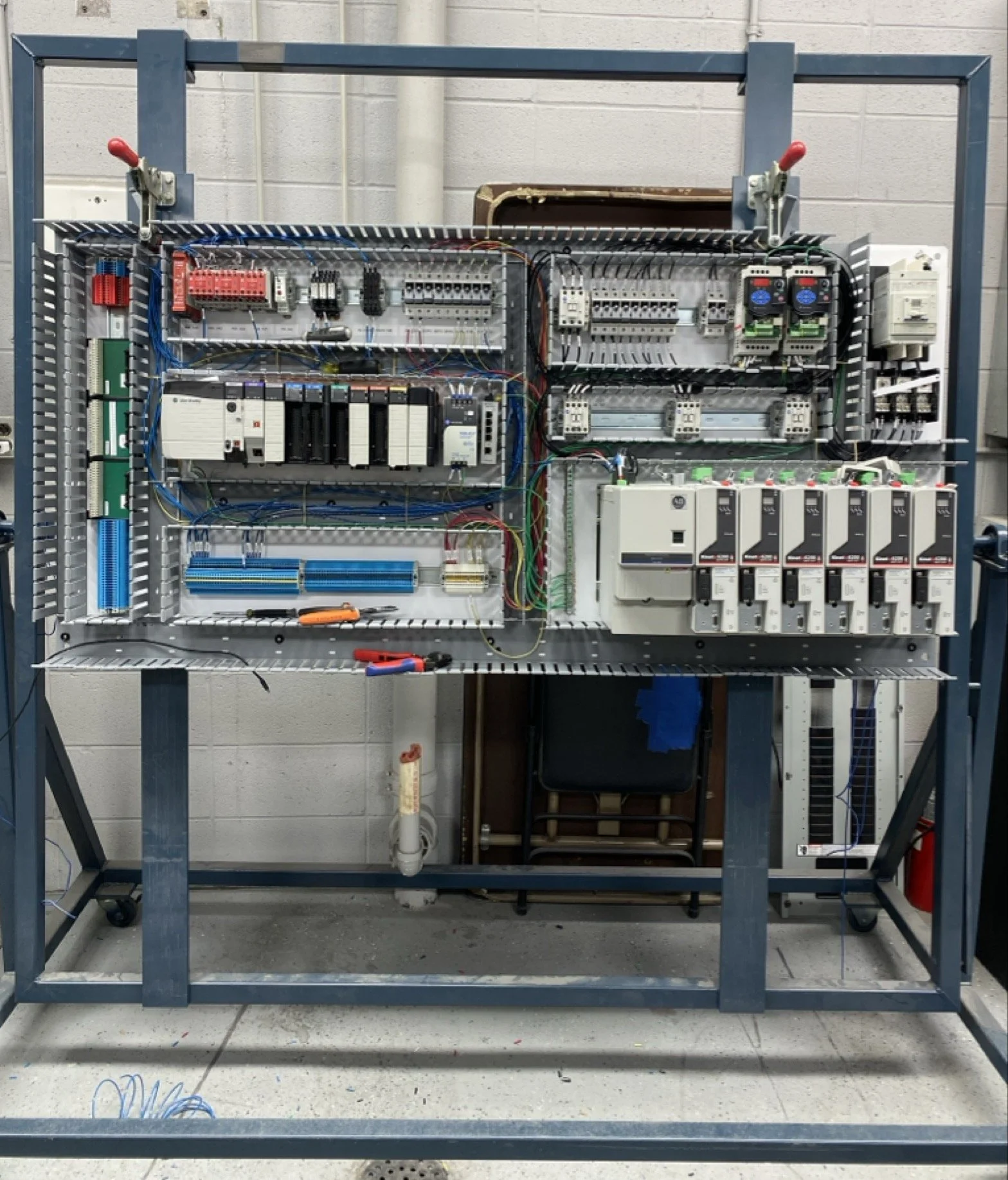 Electrical control panel mounted inside a metal frame, with various wires, switches, relays, and circuit breakers.