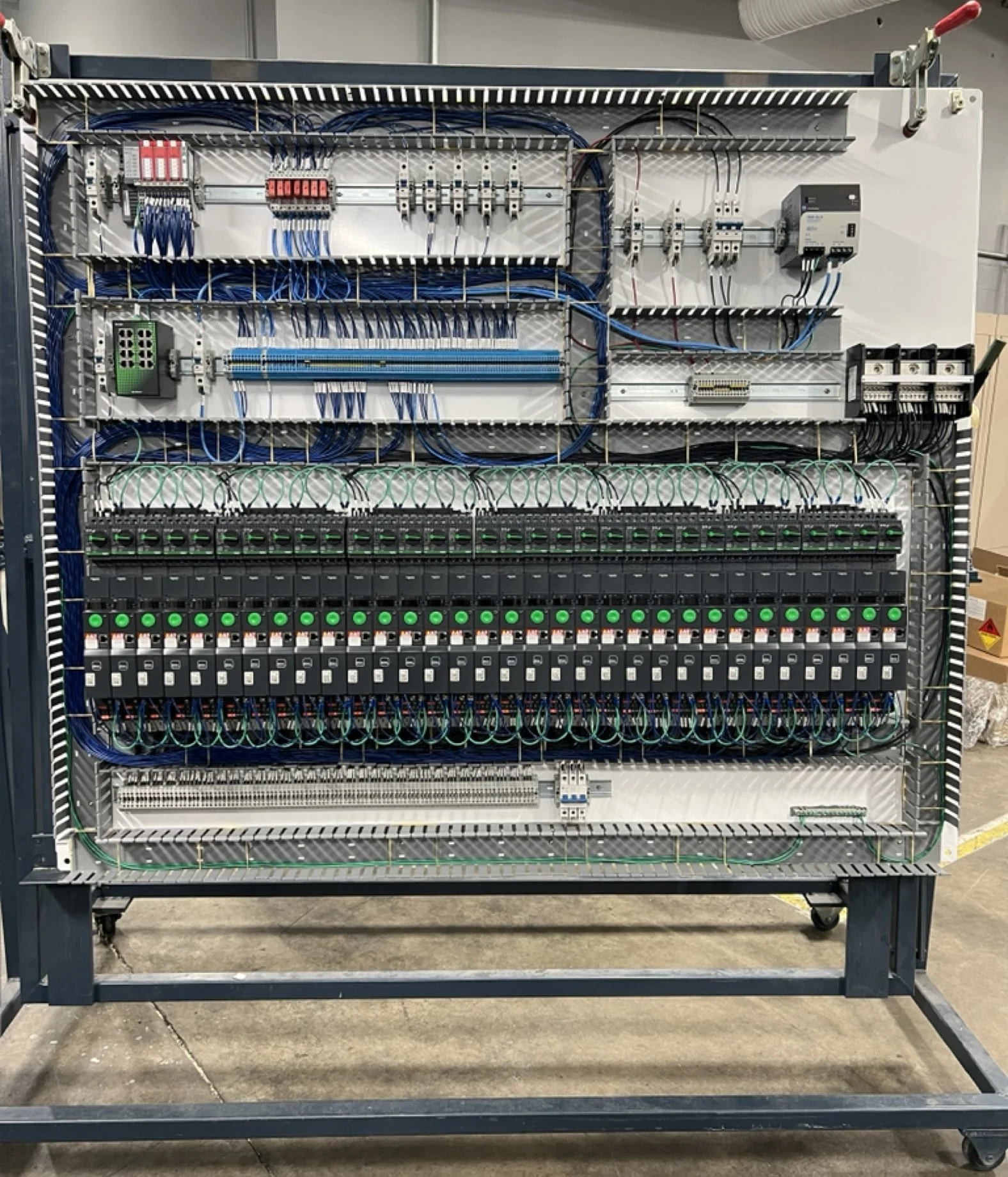 Indoor electrical control panel with various wires, switches, and components organized inside a metal frame.