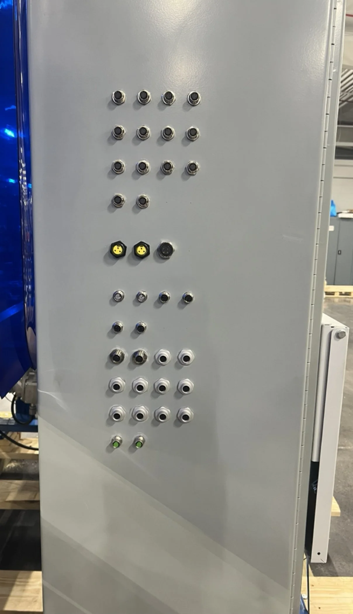 An electrical control panel with various connectors and ports arranged in rows, including some yellow connectors, white connectors, and green indicator lights at the bottom.