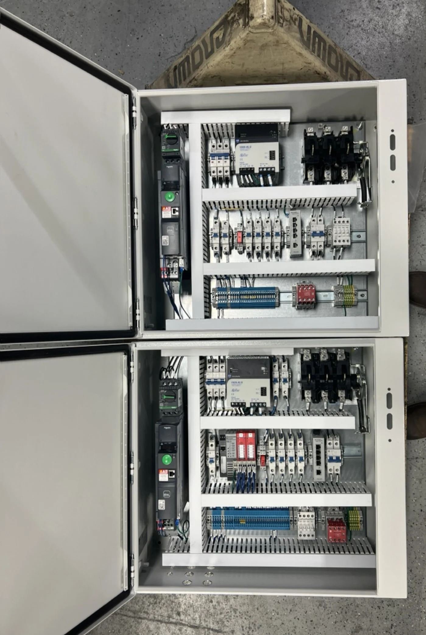 Open electrical control panel with various circuit breakers, relays, and wiring inside.
