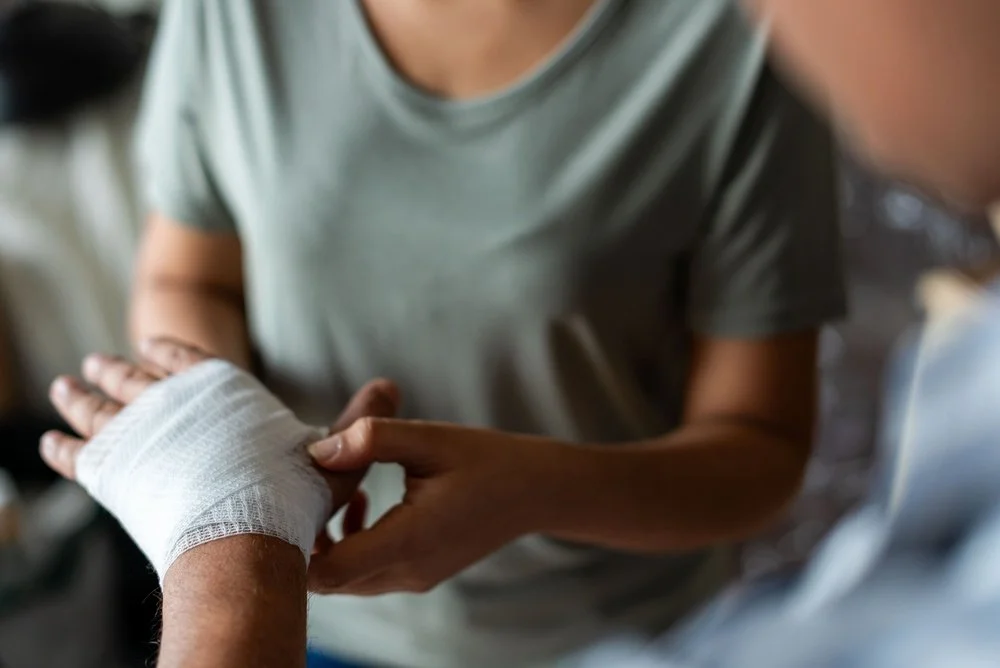 Person wrapping a bandage around another person's hand.