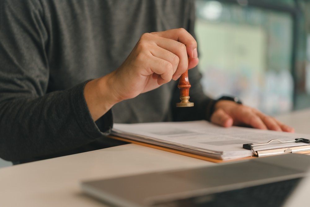 Person stamping documents at a desk.
