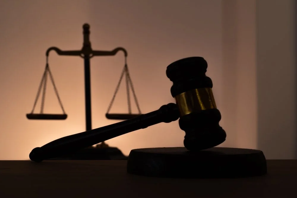 Silhouette of judicial gavel and scales of justice in the background.