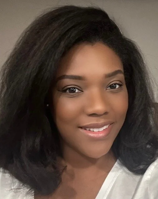 Close-up of a young African American woman with long black hair smiling at the camera.