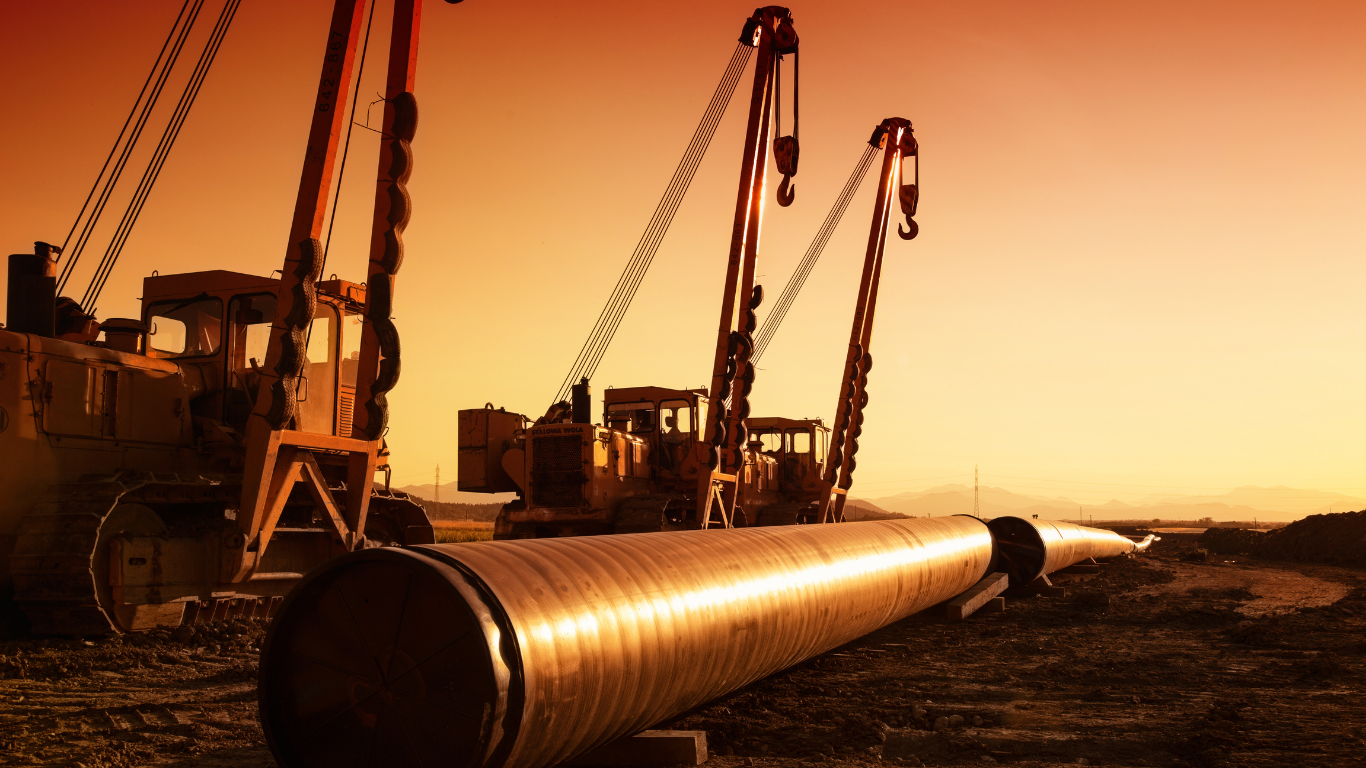 Midstream pipeline construction equipment and pipelayers installing large-diameter steel pipe along a right-of-way.