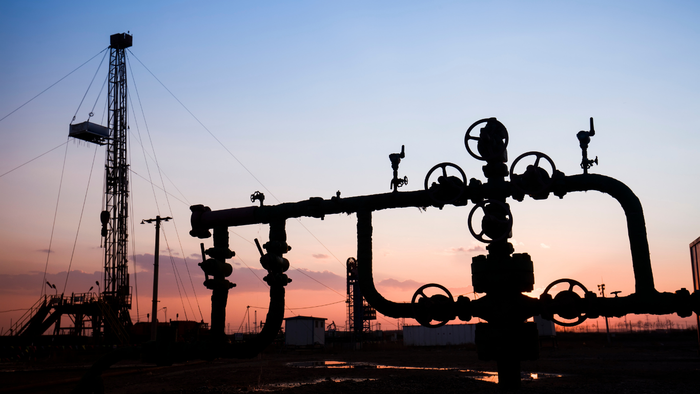 Oilfield pipeline manifold and wellhead equipment at an active Texas drilling site during sunset.