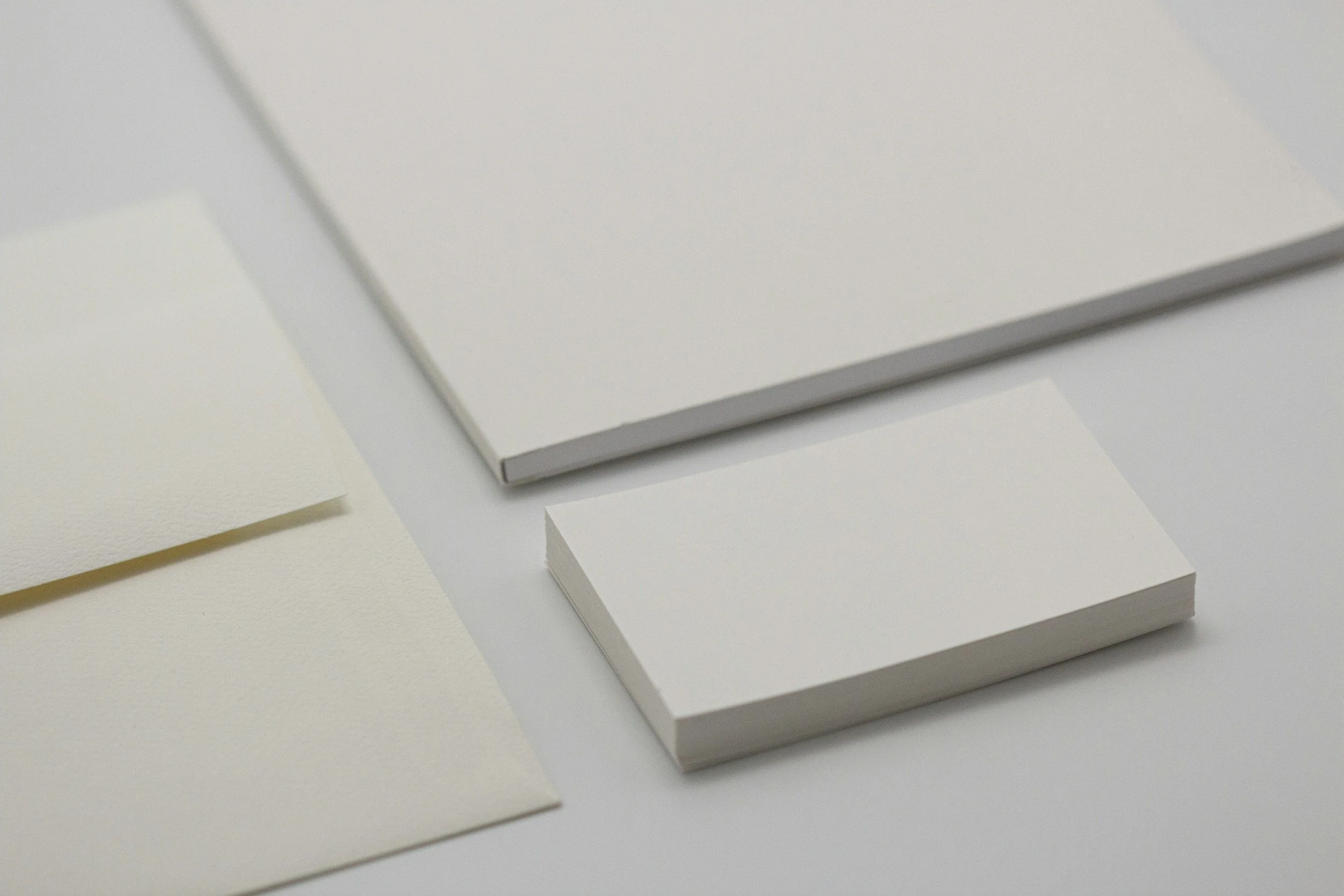 Close-up photograph of a stack of white paper, with a few sheets fanned out around it, on a white surface.