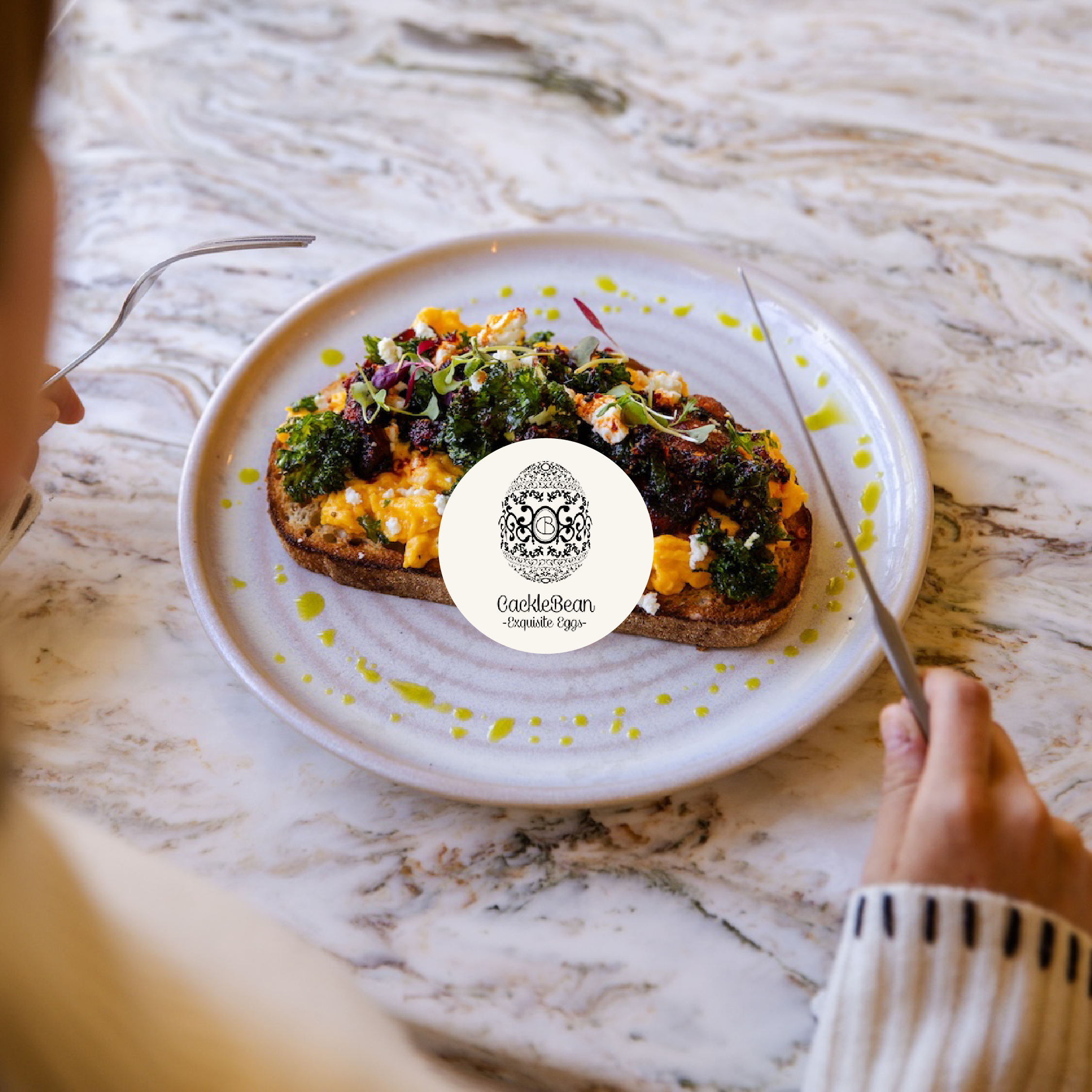 A partially eaten slice of avocado toast with toppings including eggs, microgreens, and herbs on a white plate placed on a marble table.
