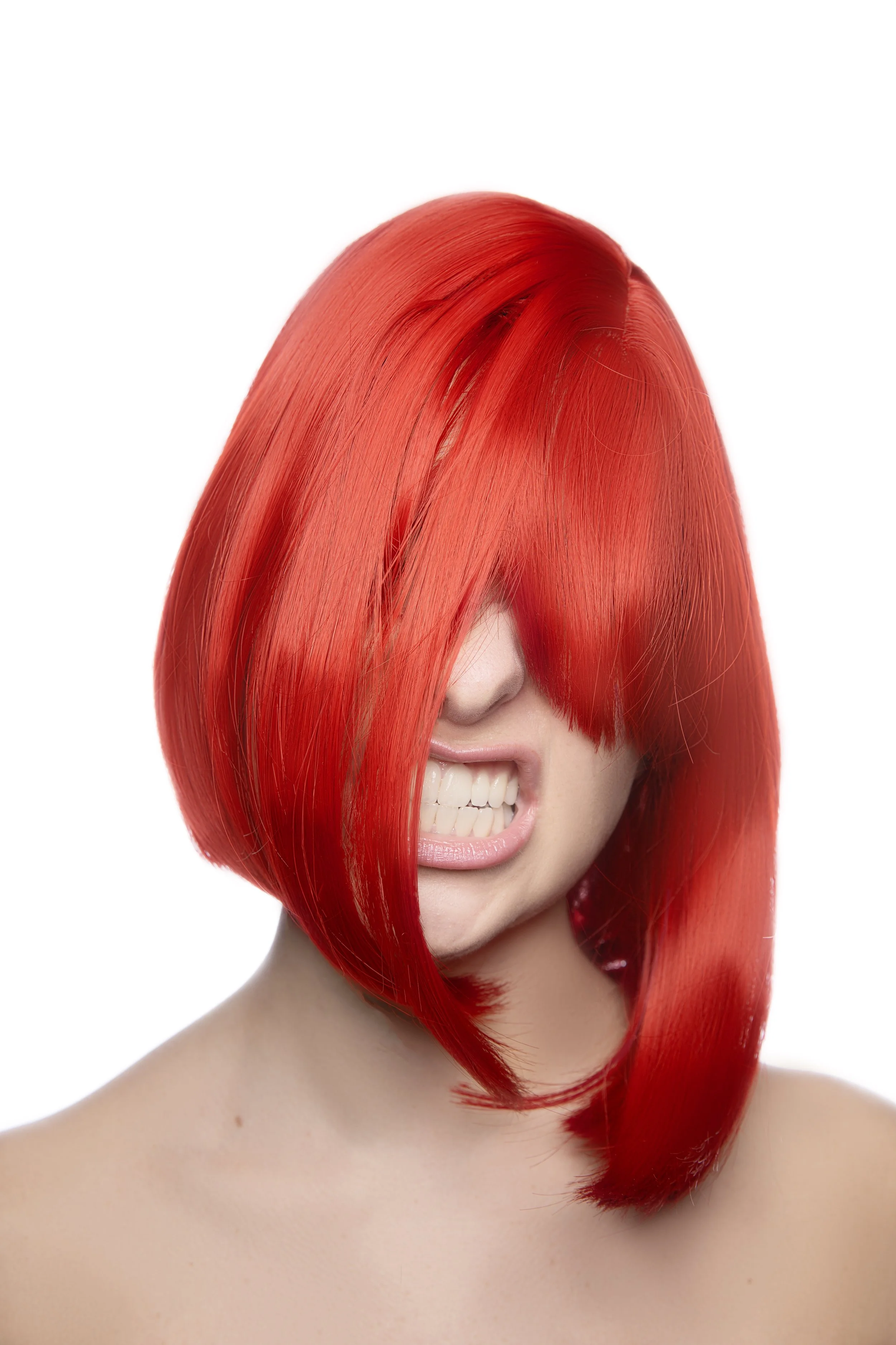 A woman with bright red, straight hair covering part of her face, showing her teeth in a playful expression, against a white background.