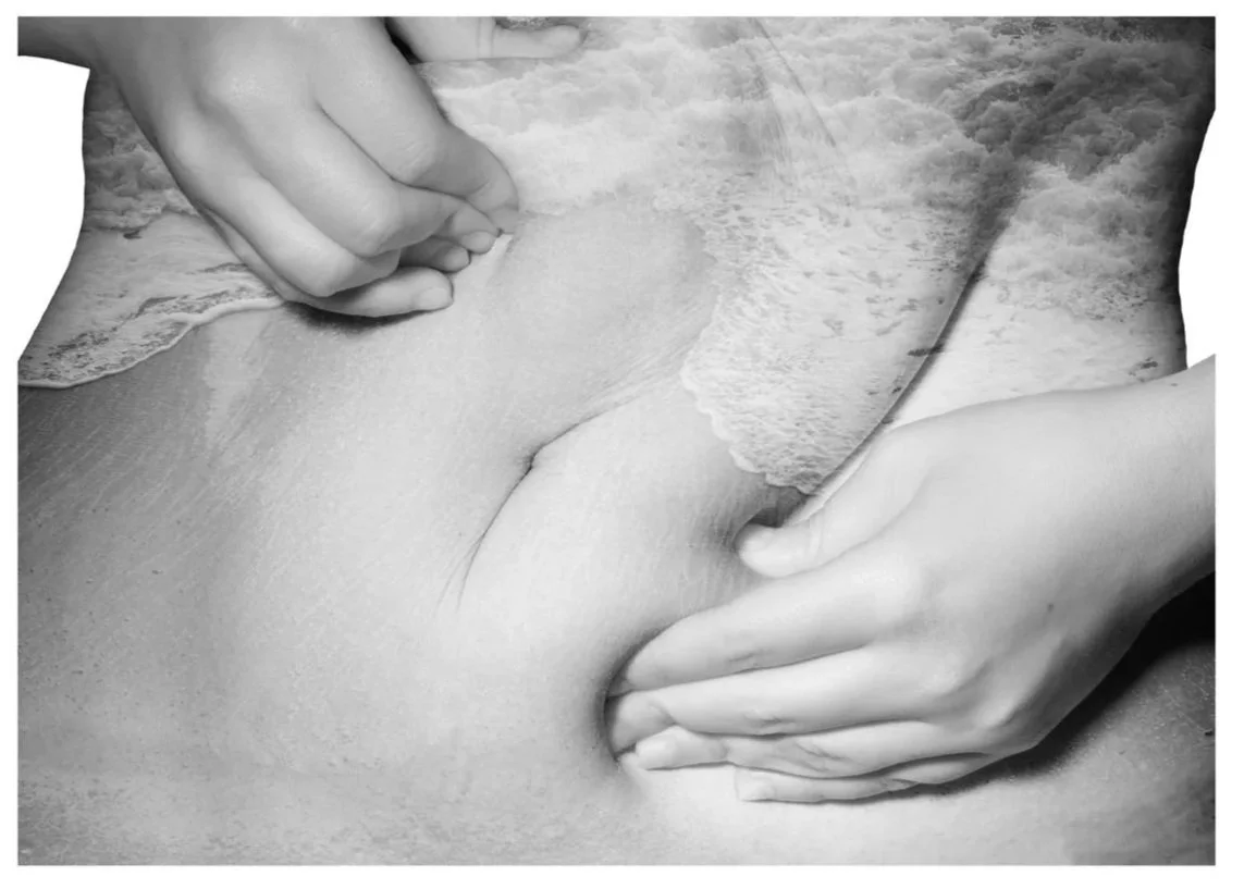 A person's hands peeling off an image of a beach with waves onto a bare skin surface, creating a layered visual effect.