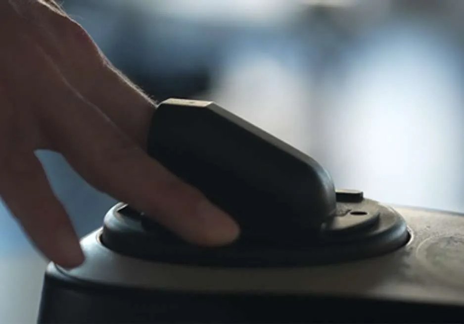 A hand pressing a button or switch on an electronic device, with a blurred background.