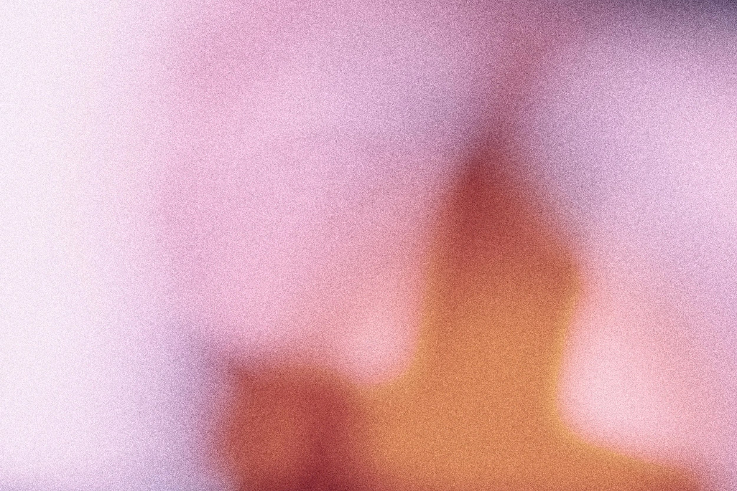 An abstract, blurred image with pastel colors and a gradient of pink, purple, and orange hues.