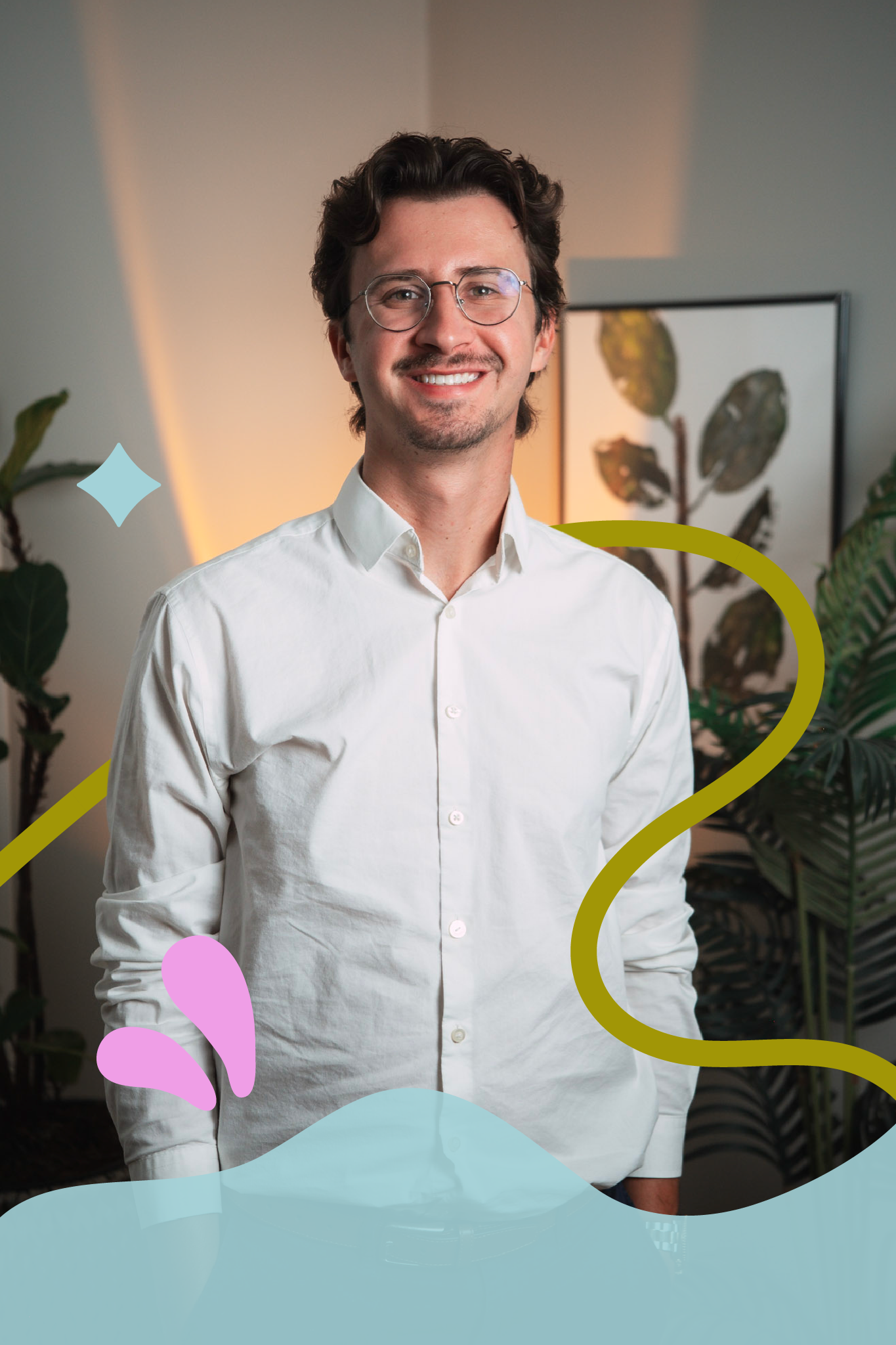 Portrait of a young man with dark wavy hair, glasses, and a mustache, smiling, wearing a white button-up shirt, standing in front of green plants and framed artwork in an indoor setting, decorated with colorful doodles and abstract shapes.