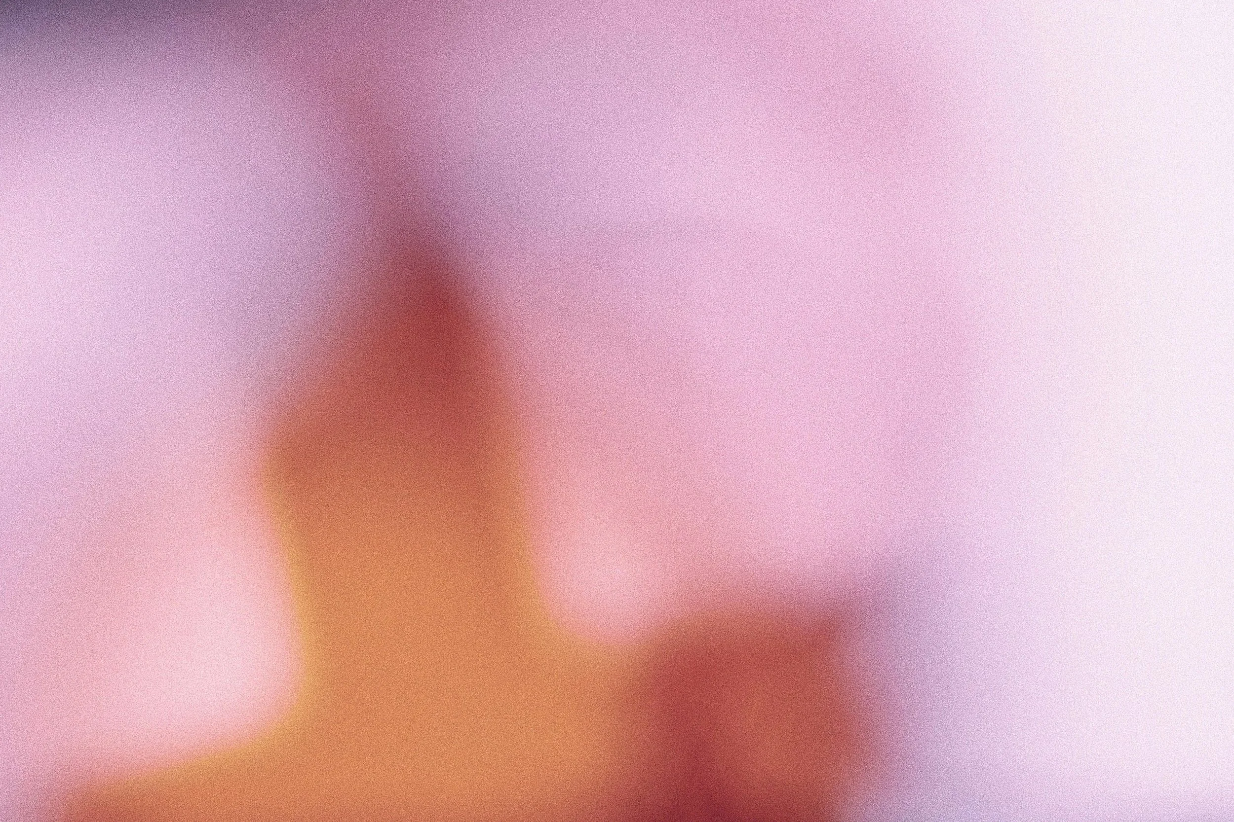 Blurred close-up of a pink and purple background with some reddish, brownish, and yellowish tones.