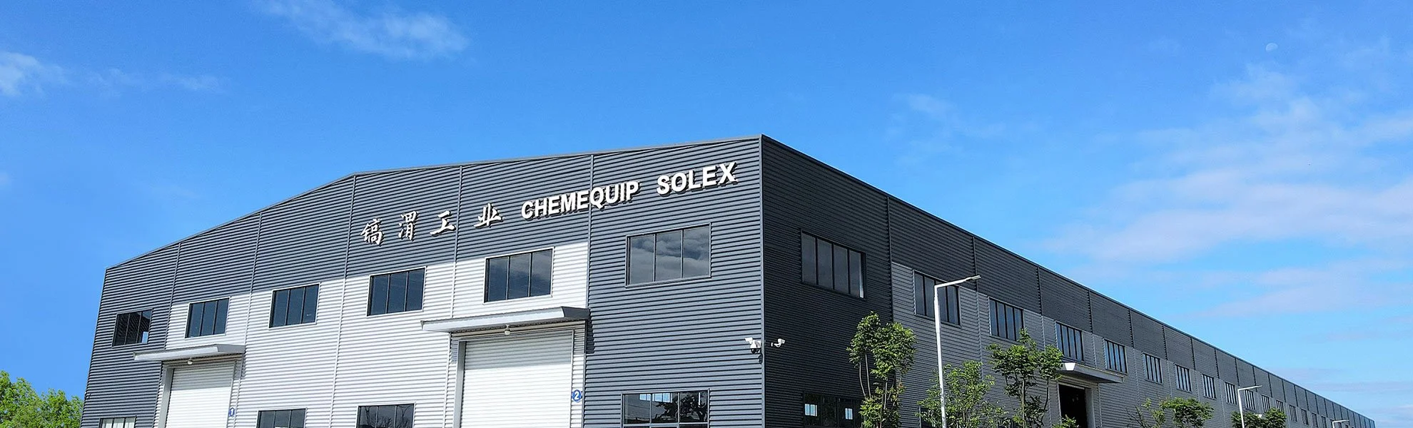 Large industrial building with metal siding, named ChemEquip Solex, under a clear blue sky.