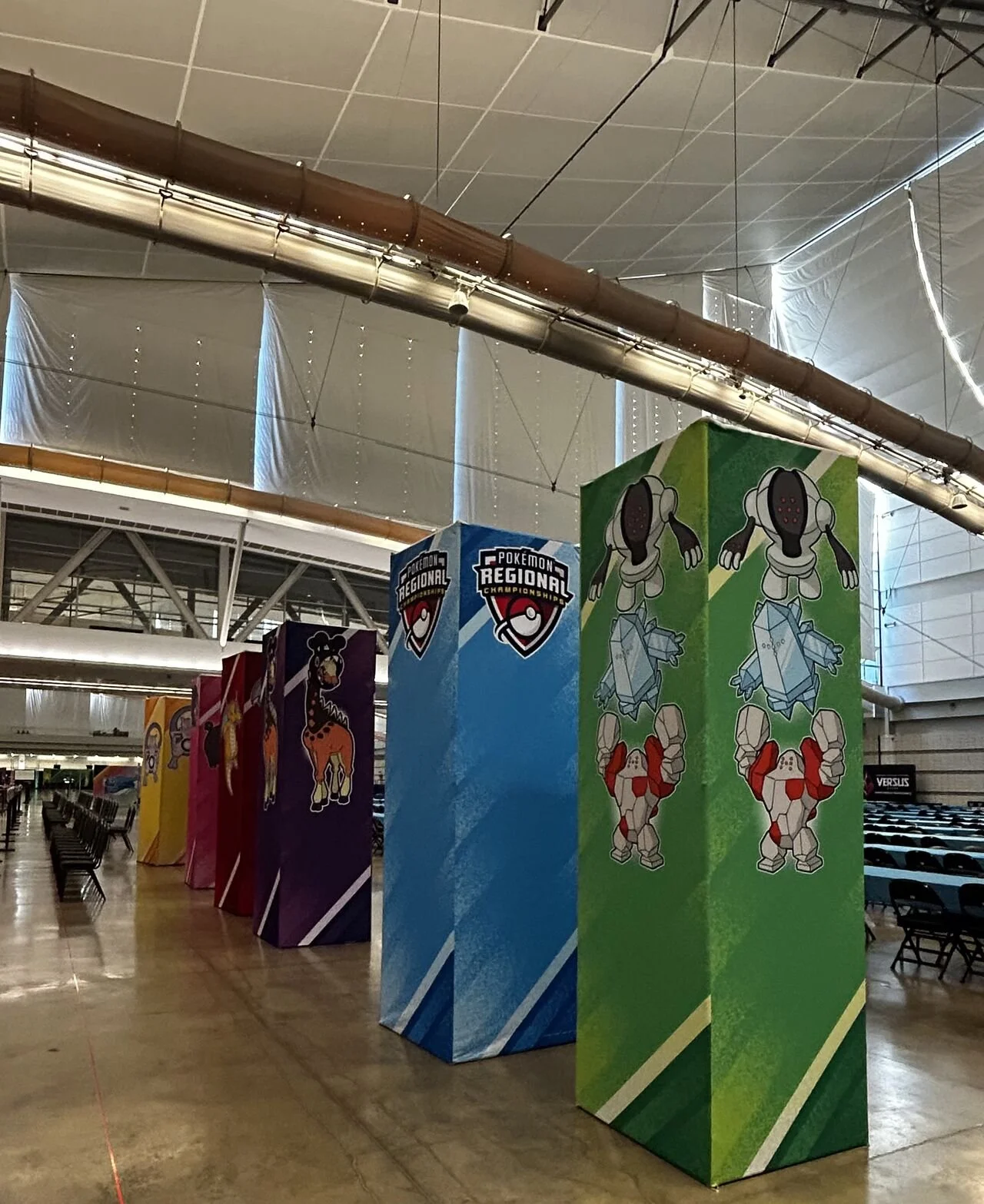 Indoor area with large banners promoting Pokémon and regional championships, featuring Pokémon characters like Garchomp and Gardevoir.