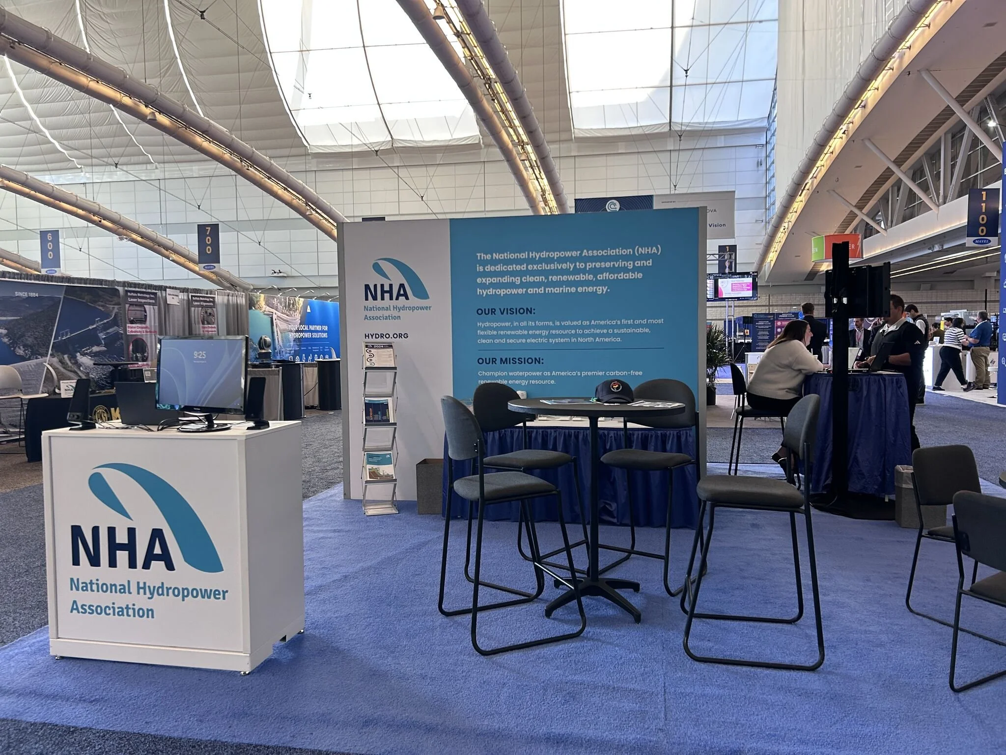 Trade show booth for the National Hydropower Association with informational displays and people talking.