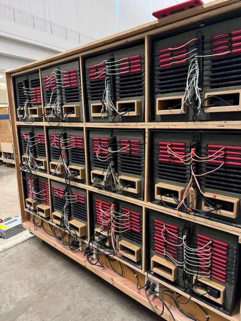 Open battery bank with rows of red and black batteries connected by wires.