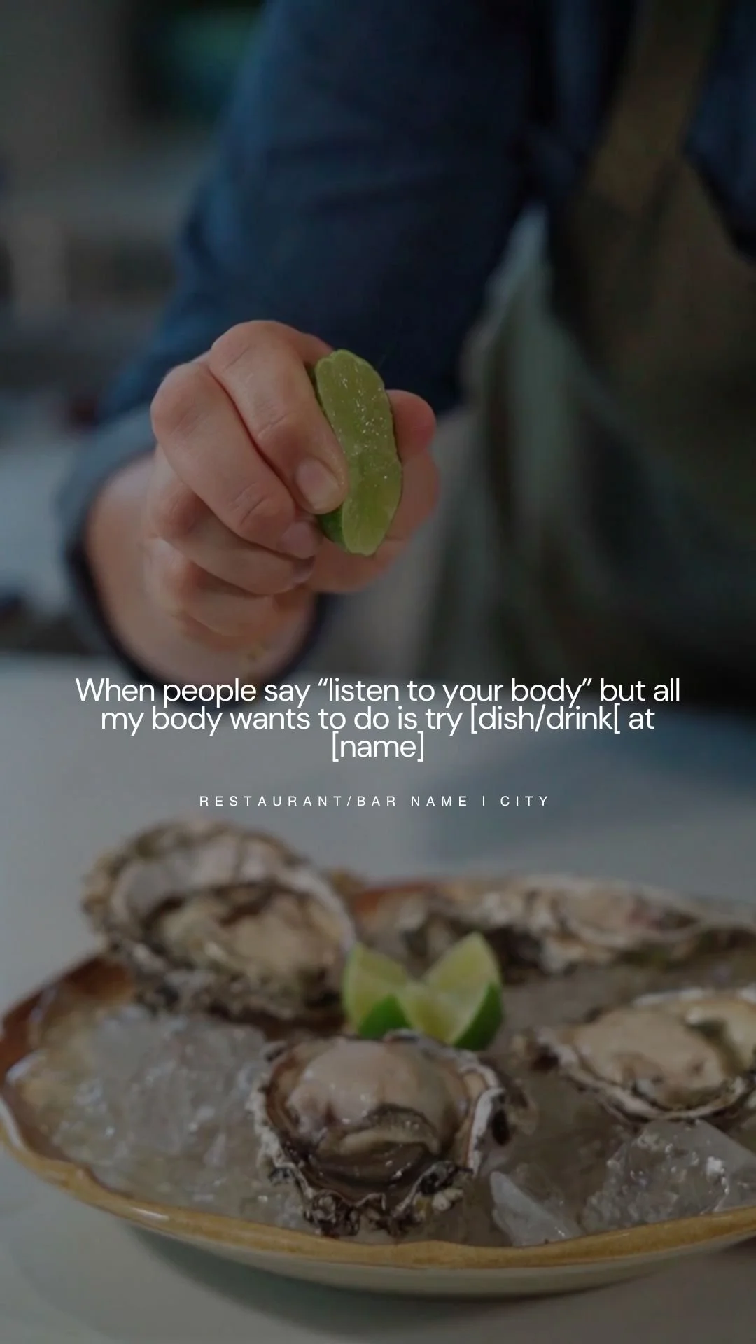 A hand holding a slice of lime in front of a plate of oysters on ice garnished with lime wedges.