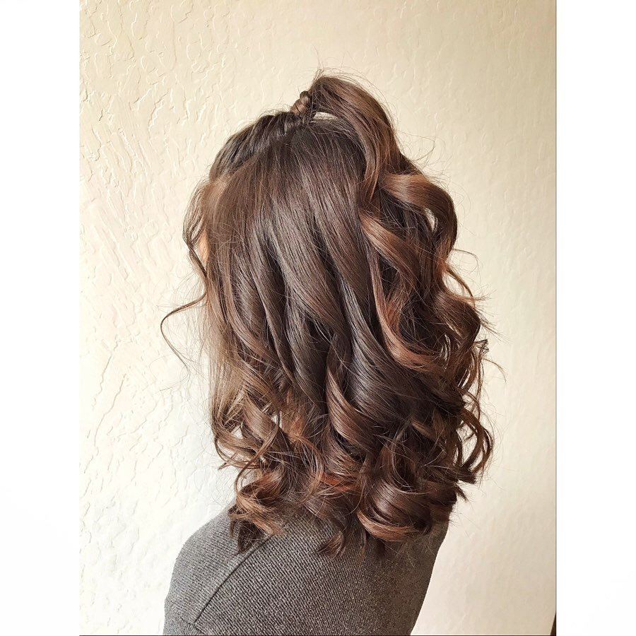 Woman with shoulder-length, wavy, light brown hair styled in loose curls.
