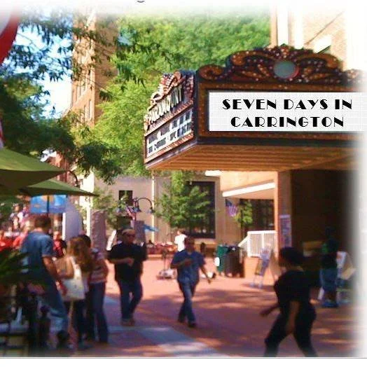 People walking near a theater marquee displaying "Seven Days in Carrington" on a sunny day