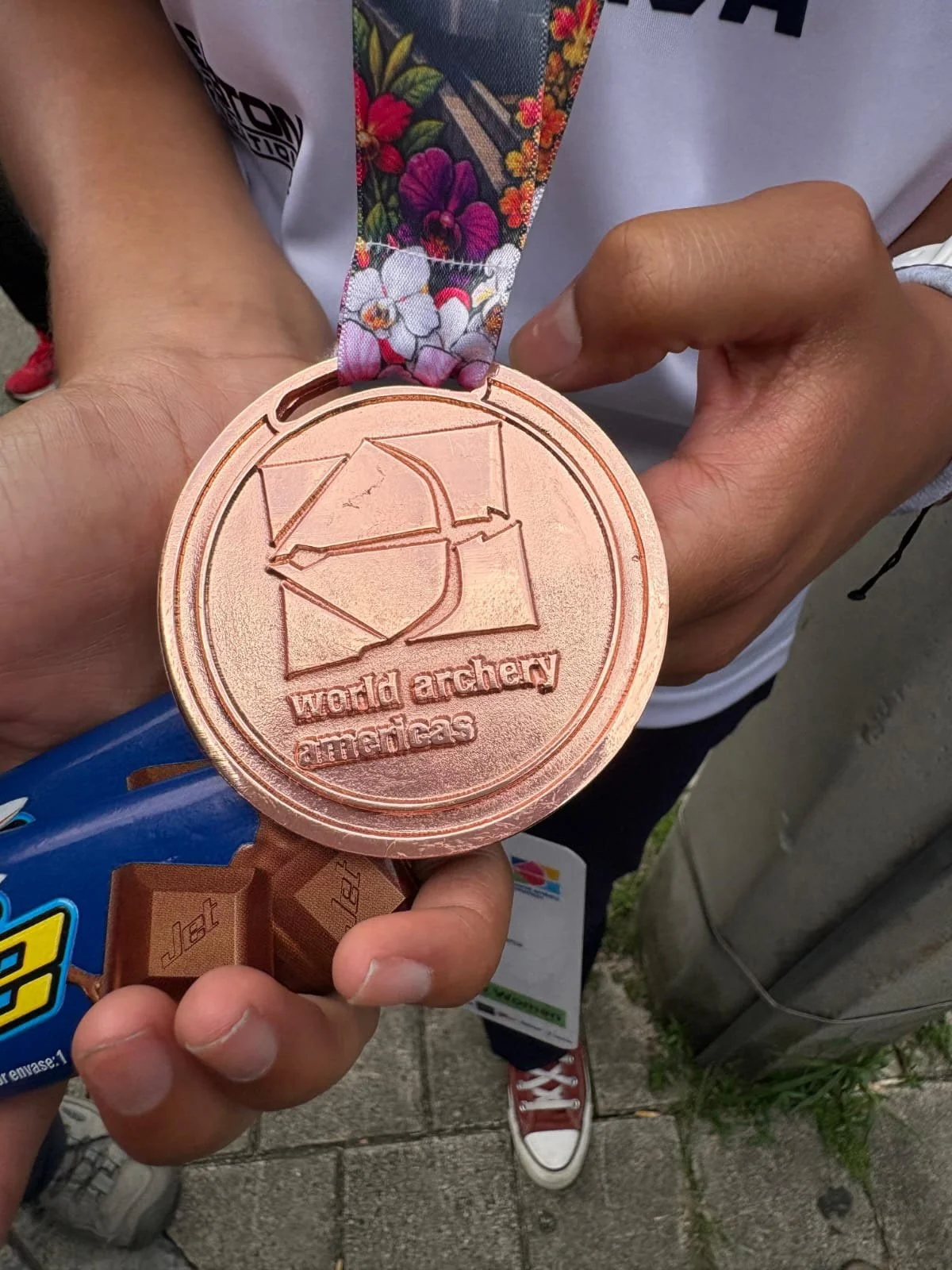 A person holding a bronze medal for the World Archery Americas competition, held in Medellin, Colombia.