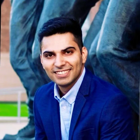 A smiling man in a blue blazer and light blue shirt.