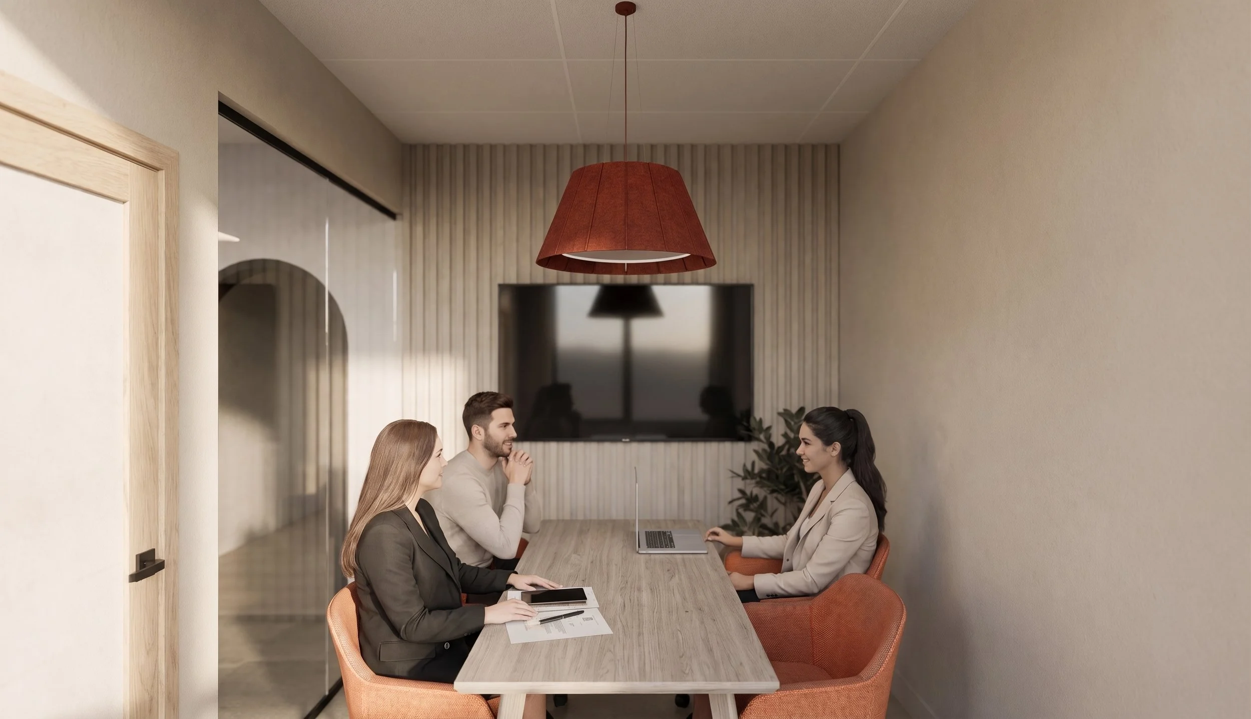 Quatre personnes assises autour d'une table de réunion dans une salle de bureau moderne, discutant, avec un grand écran à l'arrière et une lampe suspendue rouge au plafond.