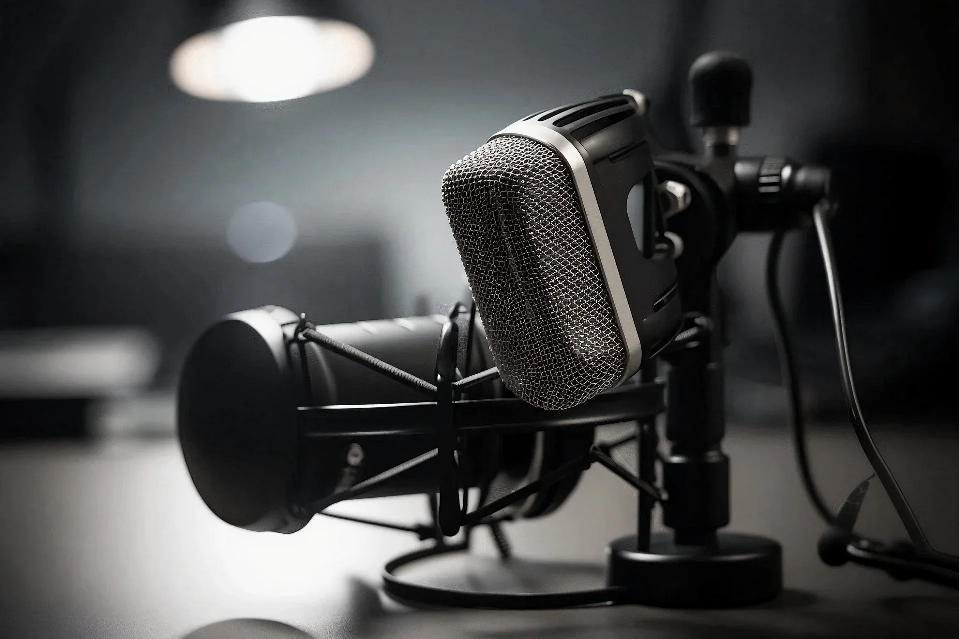 A professional studio microphone mounted on a stand in a dimly lit room.
