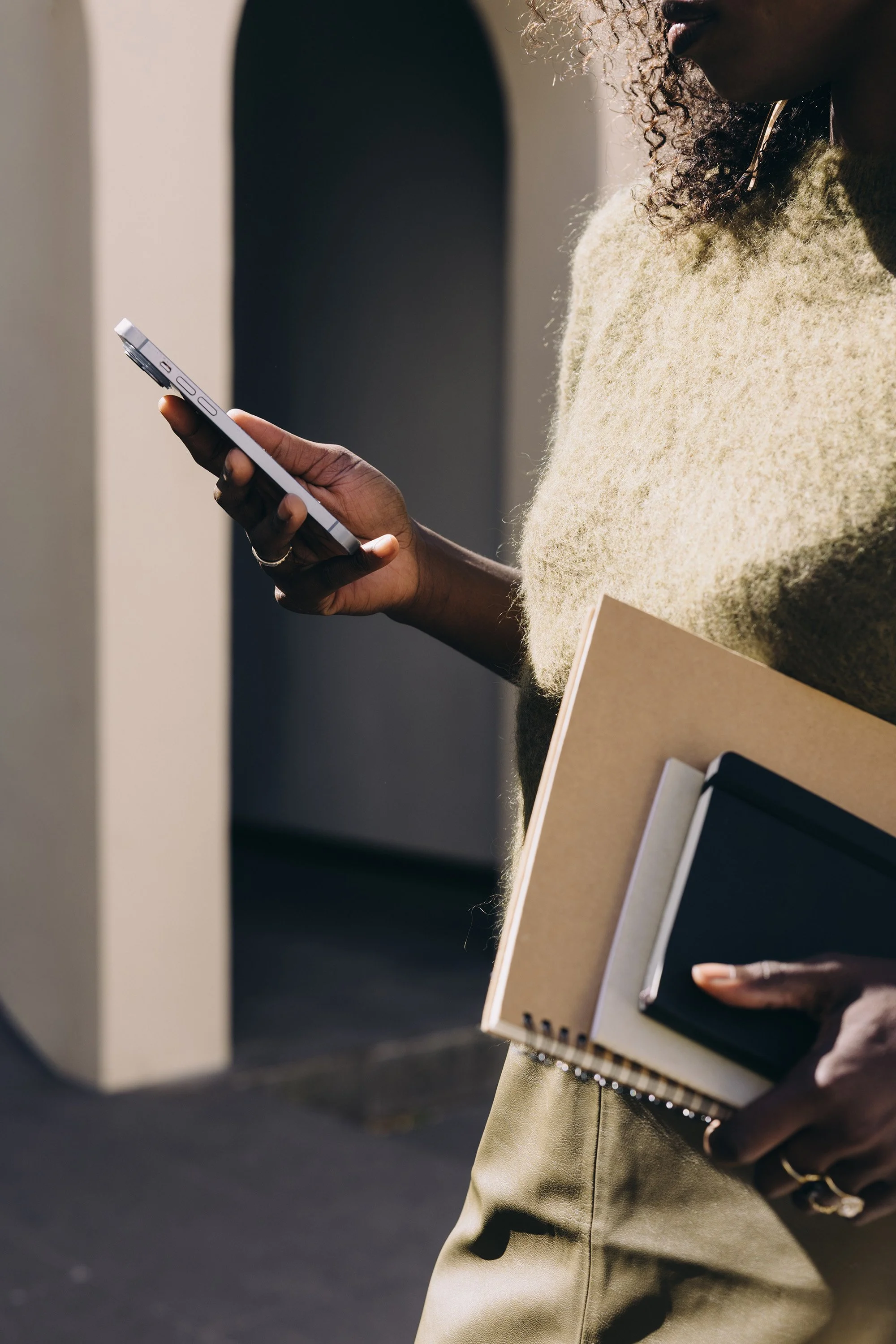 Woman walking with a phone and notebook in hand, representing strategic alignment on priorities.