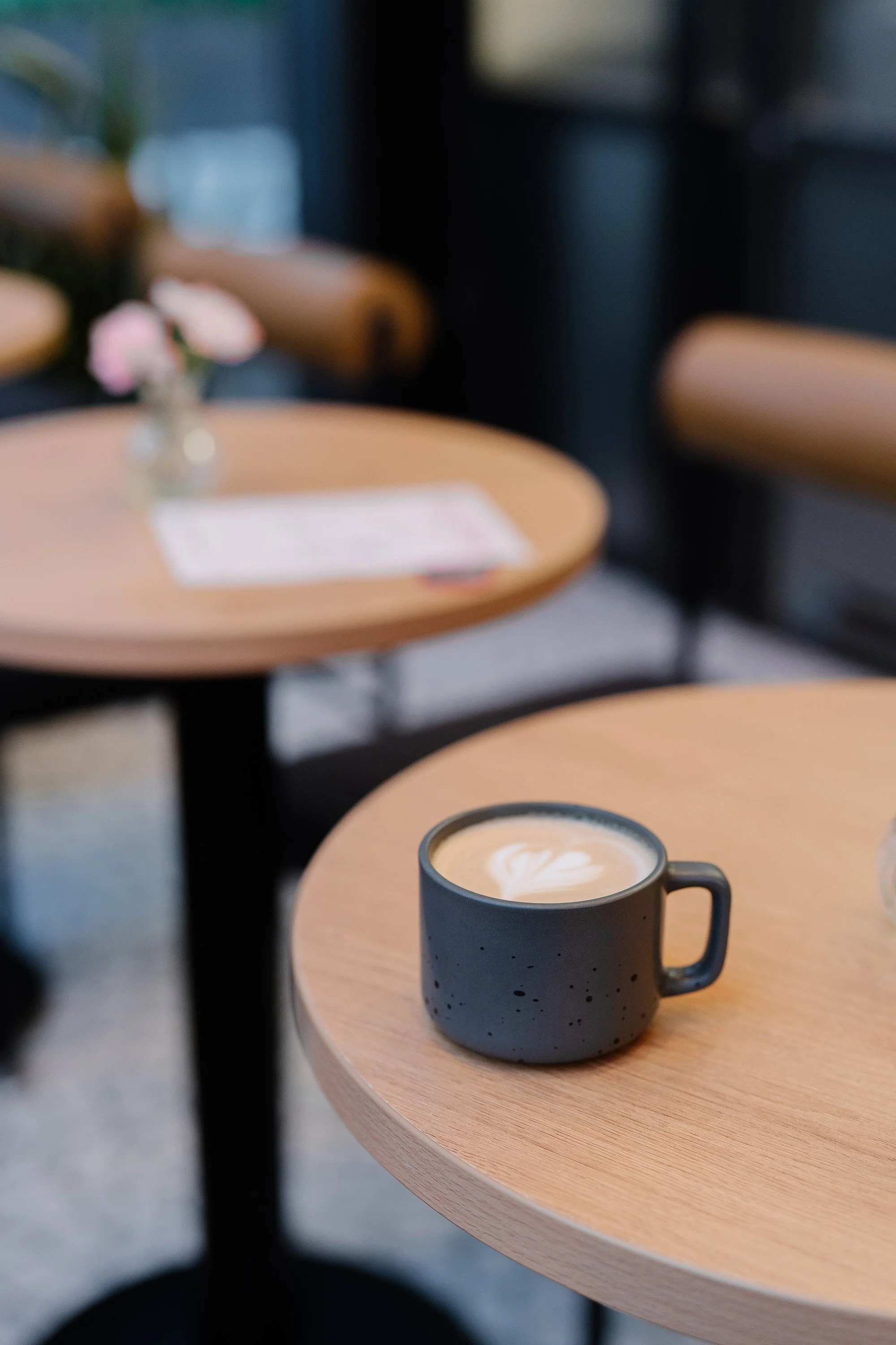 A latte on a wooden café table, setting an inviting tone for starting a conversation.
