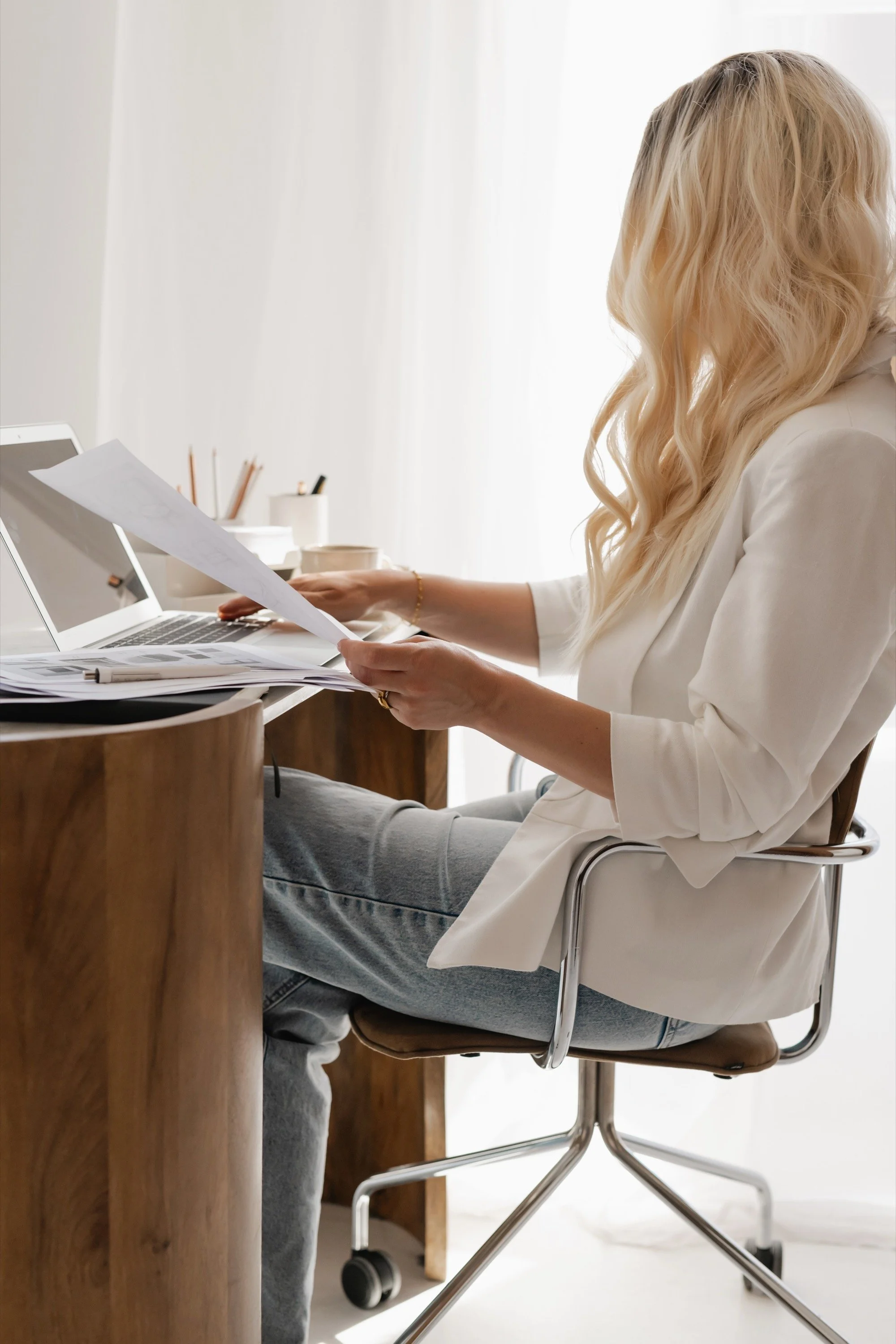 Woman reviewing documents and working at a laptop, representing a deep organizational assessment.