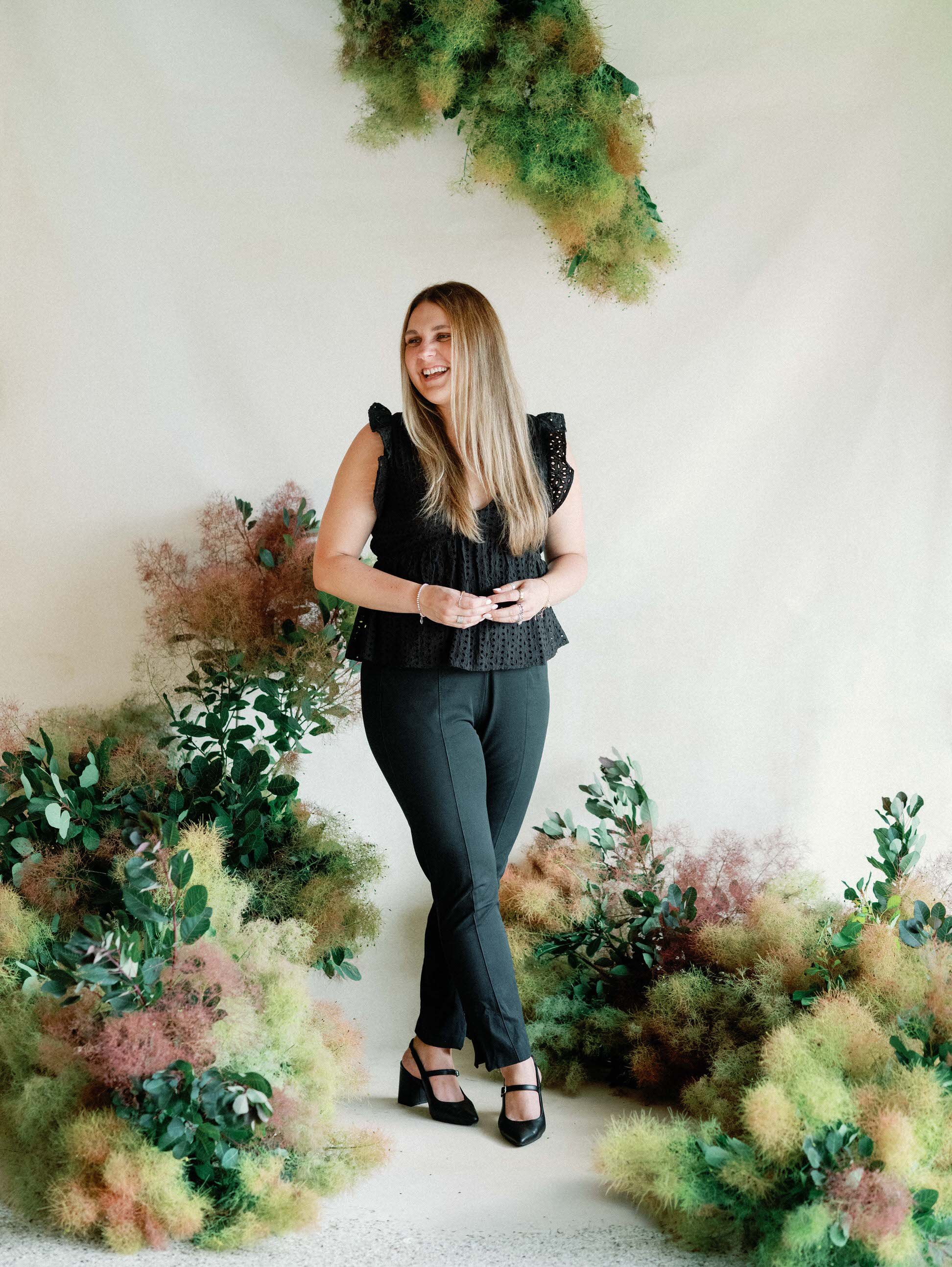 Melissa Hansen, design lead at RBC standing in smoke bush installation in all black outfit